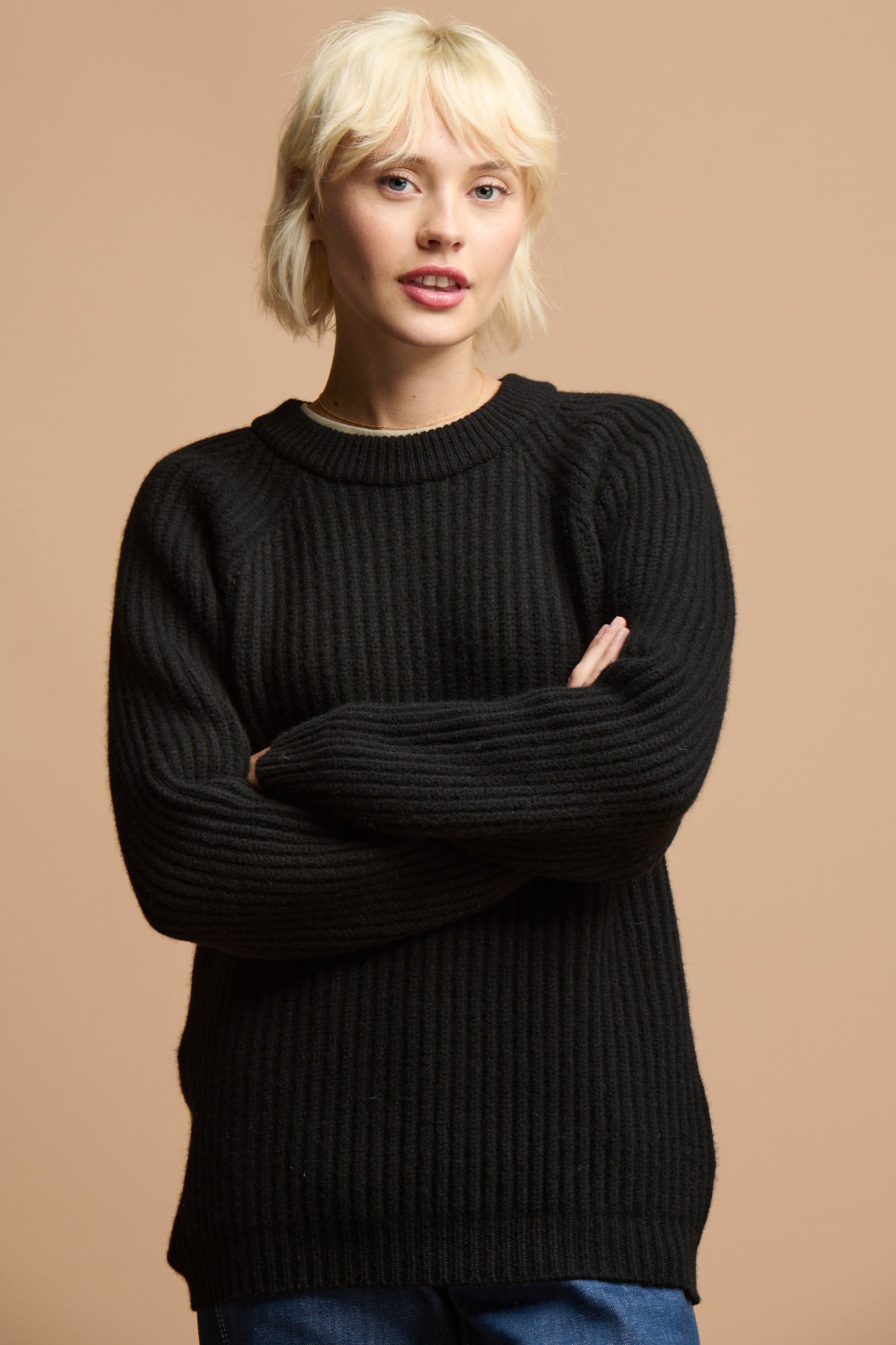 Thigh up of female with her arms folded wearing lambswool fisherman ribbed jumper in black 