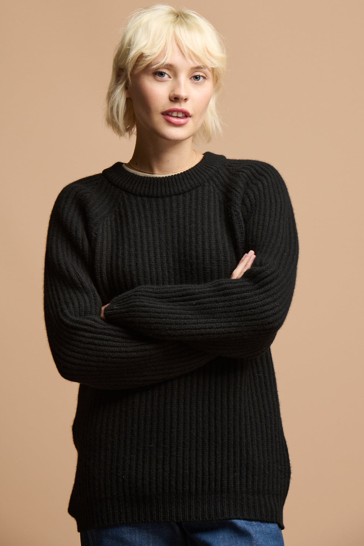 Thigh up of female with her arms folded wearing lambswool fisherman ribbed jumper in black