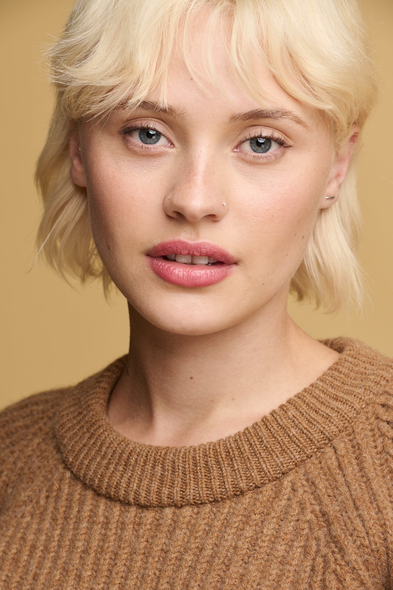 portrait of female wearing lambswool fisherman ribbed jumper in dark camel showing close up detail of the thick knit