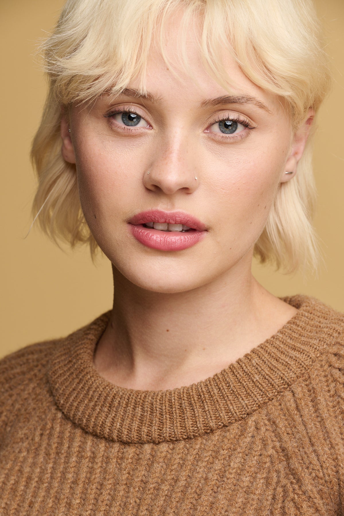 
            portrait of female wearing lambswool fisherman ribbed jumper in dark camel showing close up detail of the thick knit