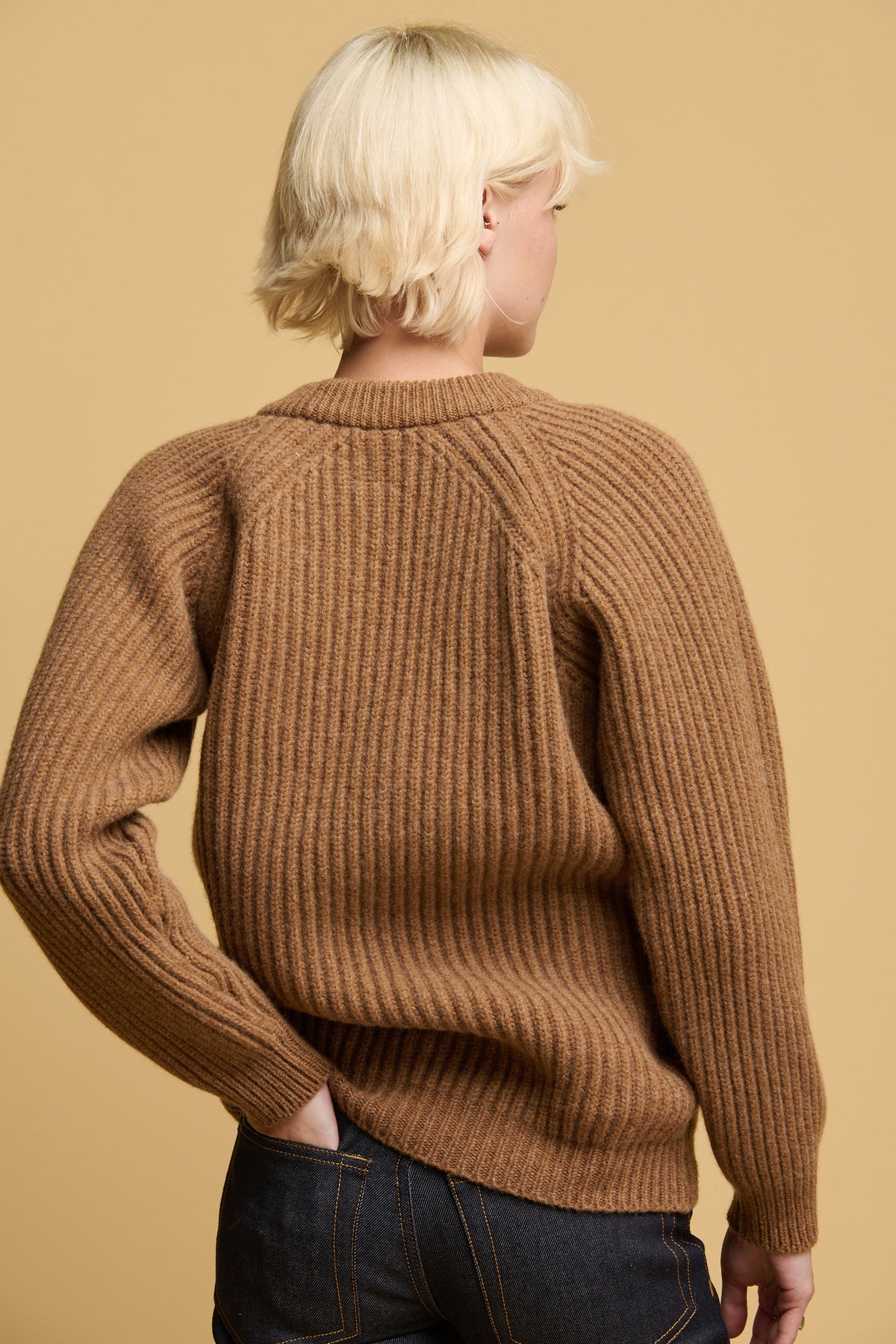 The back of female wearing lambswool fisherman ribbed jumper in dark camel