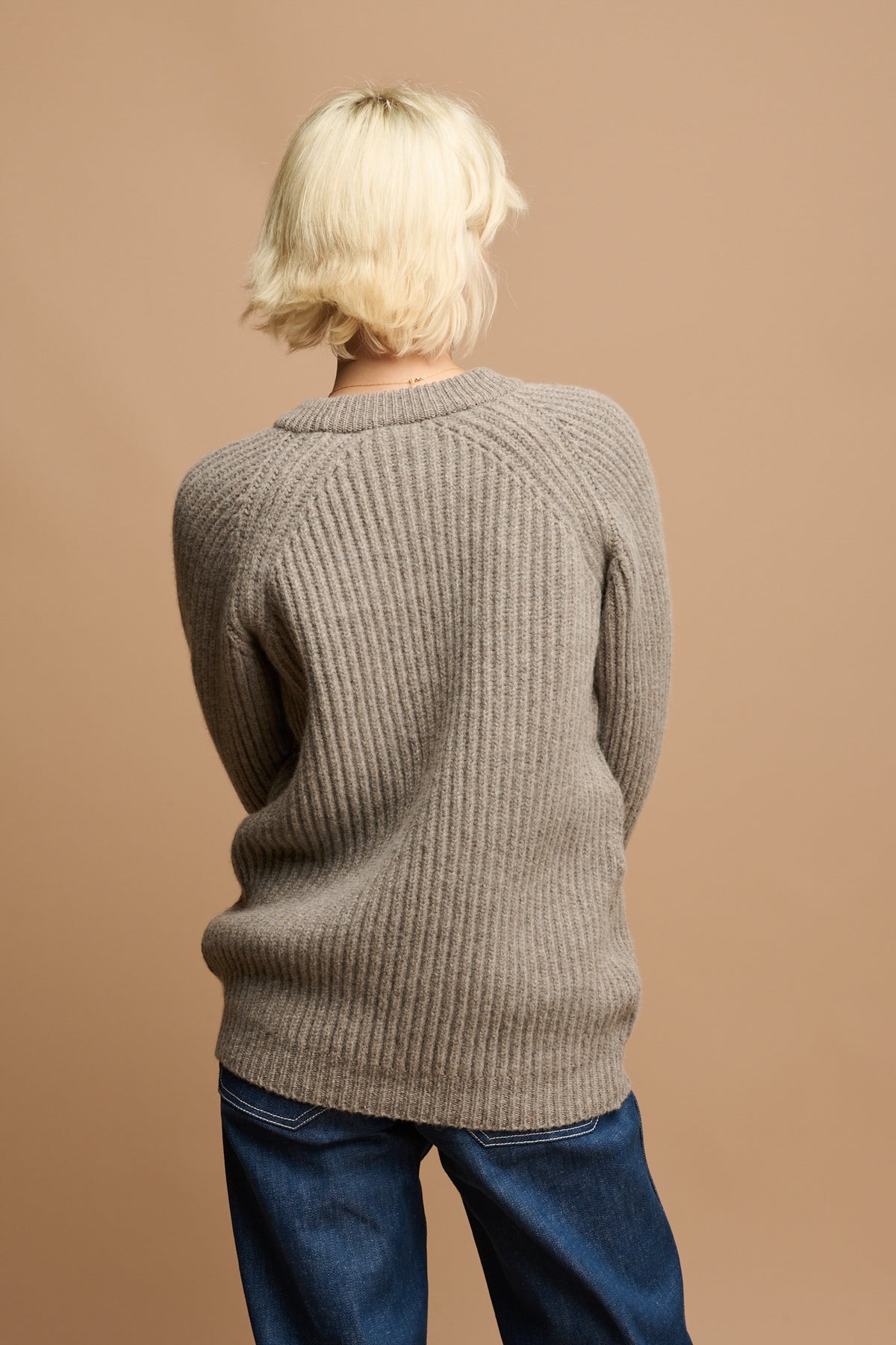 
            The back of female wearing lambswool fisherman jumper in truffle 