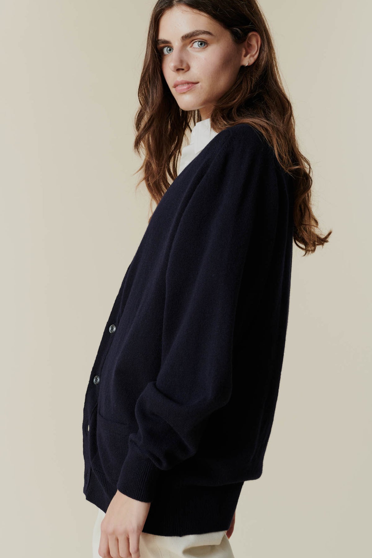 Brunette female wearing unbuttoned lambswool v neck cardigan side