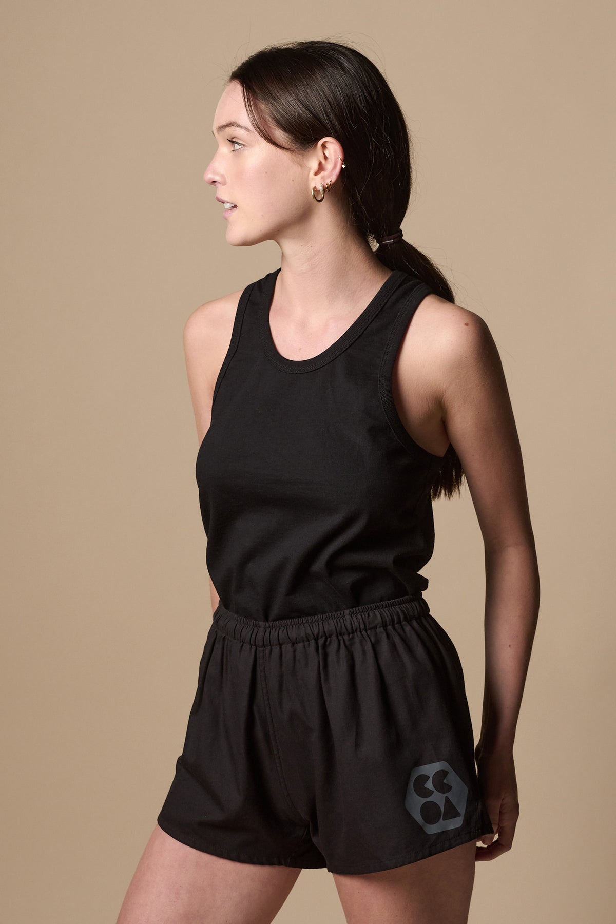 
            Thigh up image of female wearing lightweight sports short plastic free in black with CCOA logo on left leg