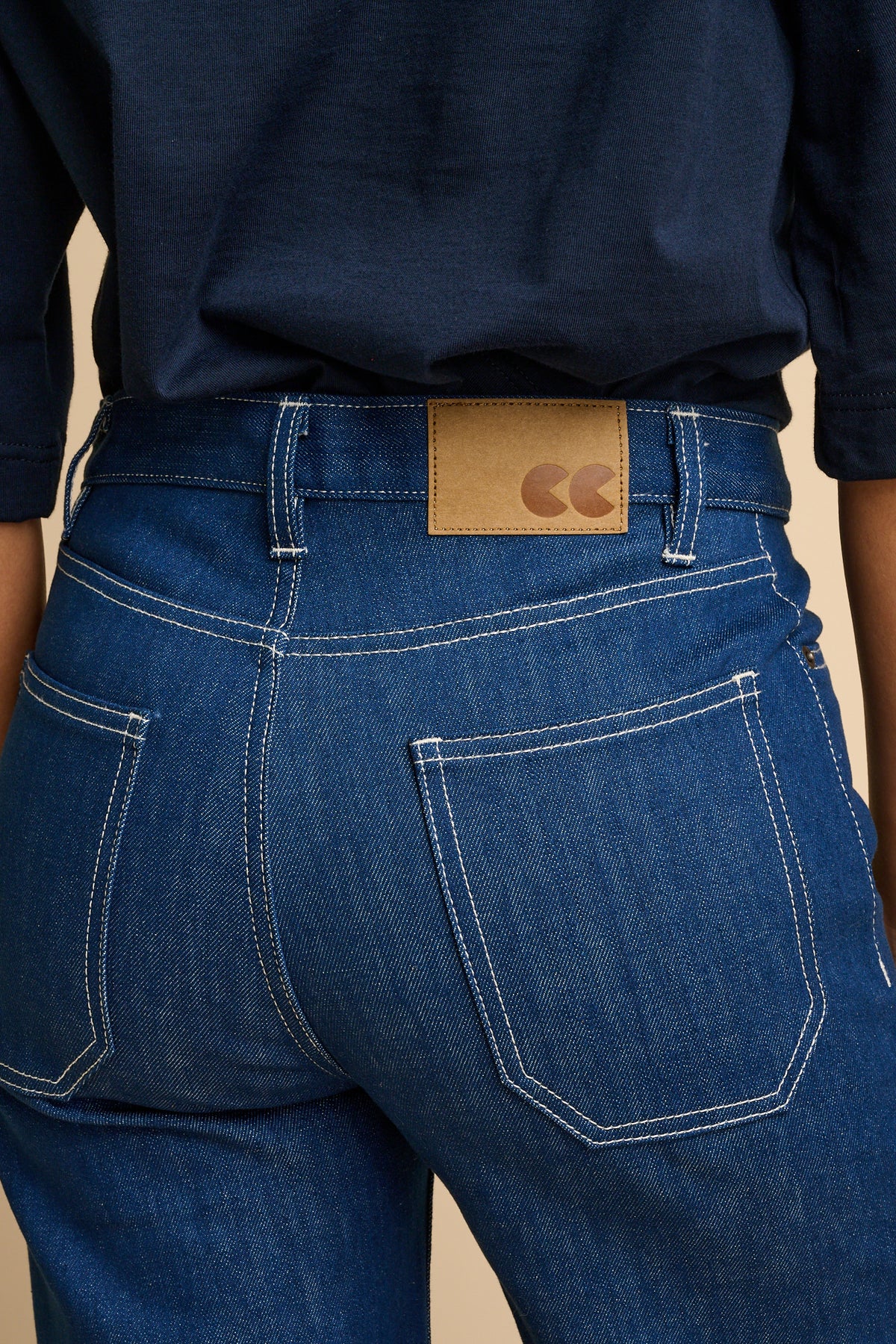 Woman wearing blue jeans with logo jeans patch.