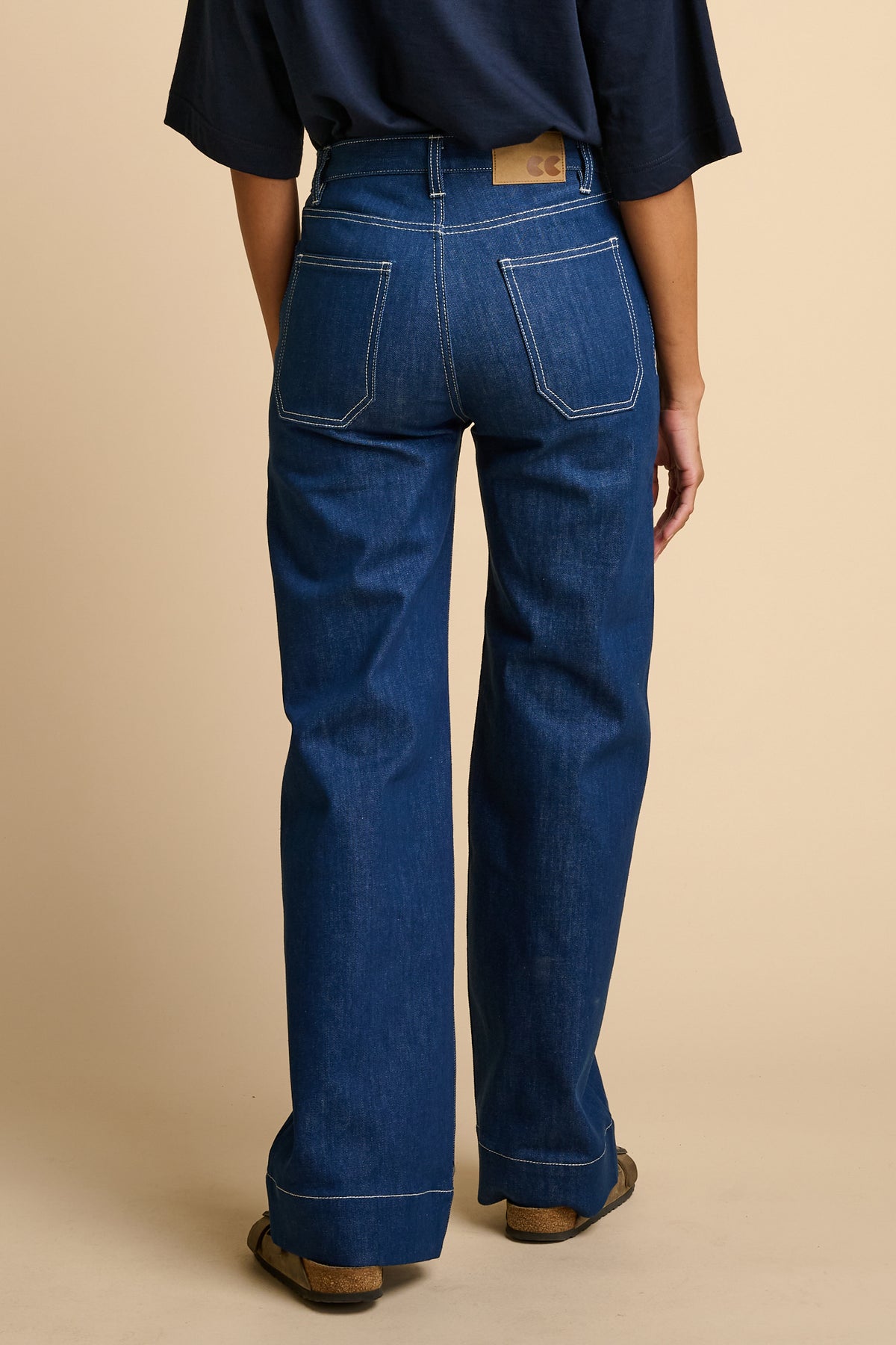 Woman wearing blue jeans on a beige background