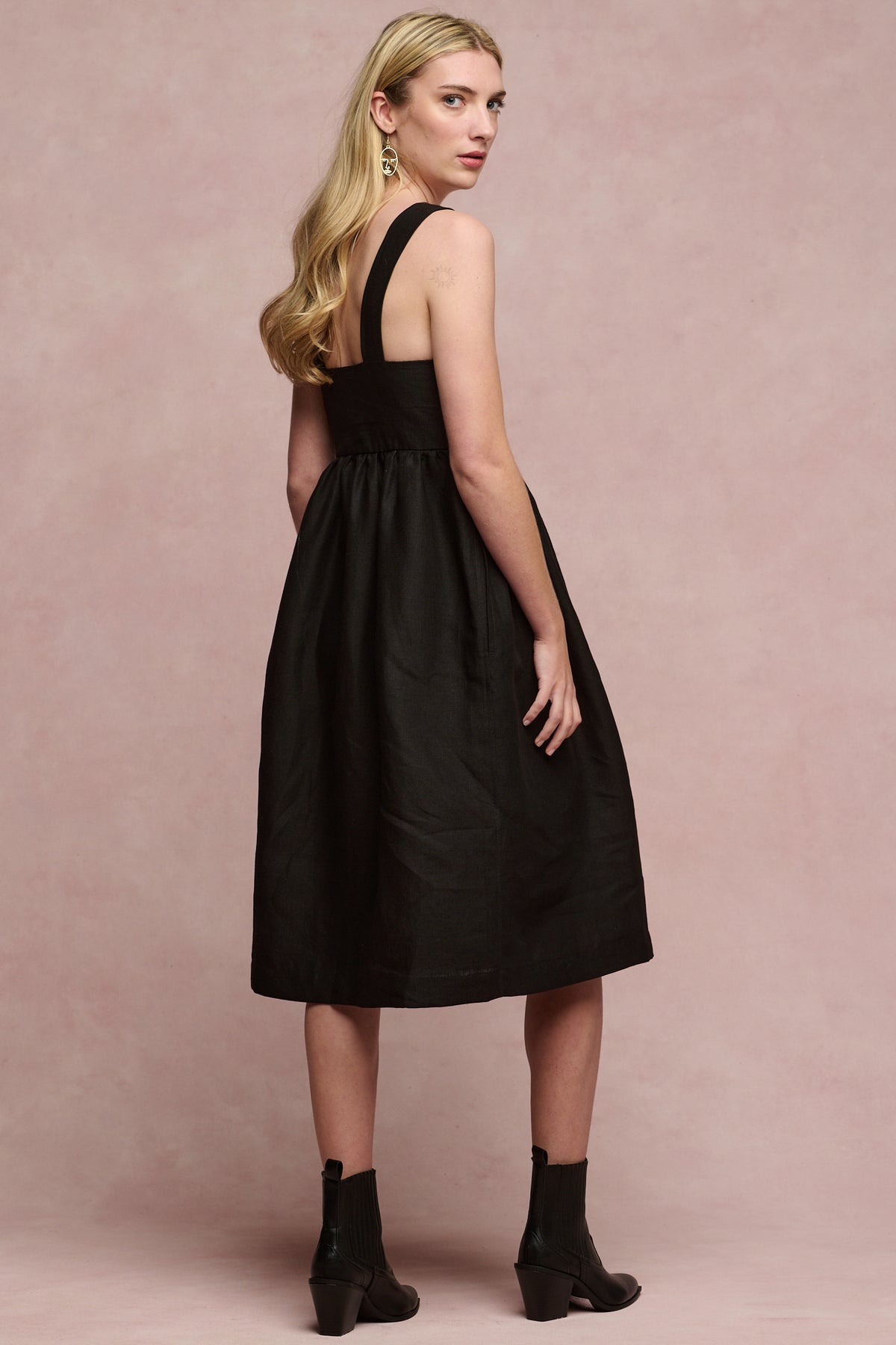 back of female with long blonde hair wearing linen sun dress in black
