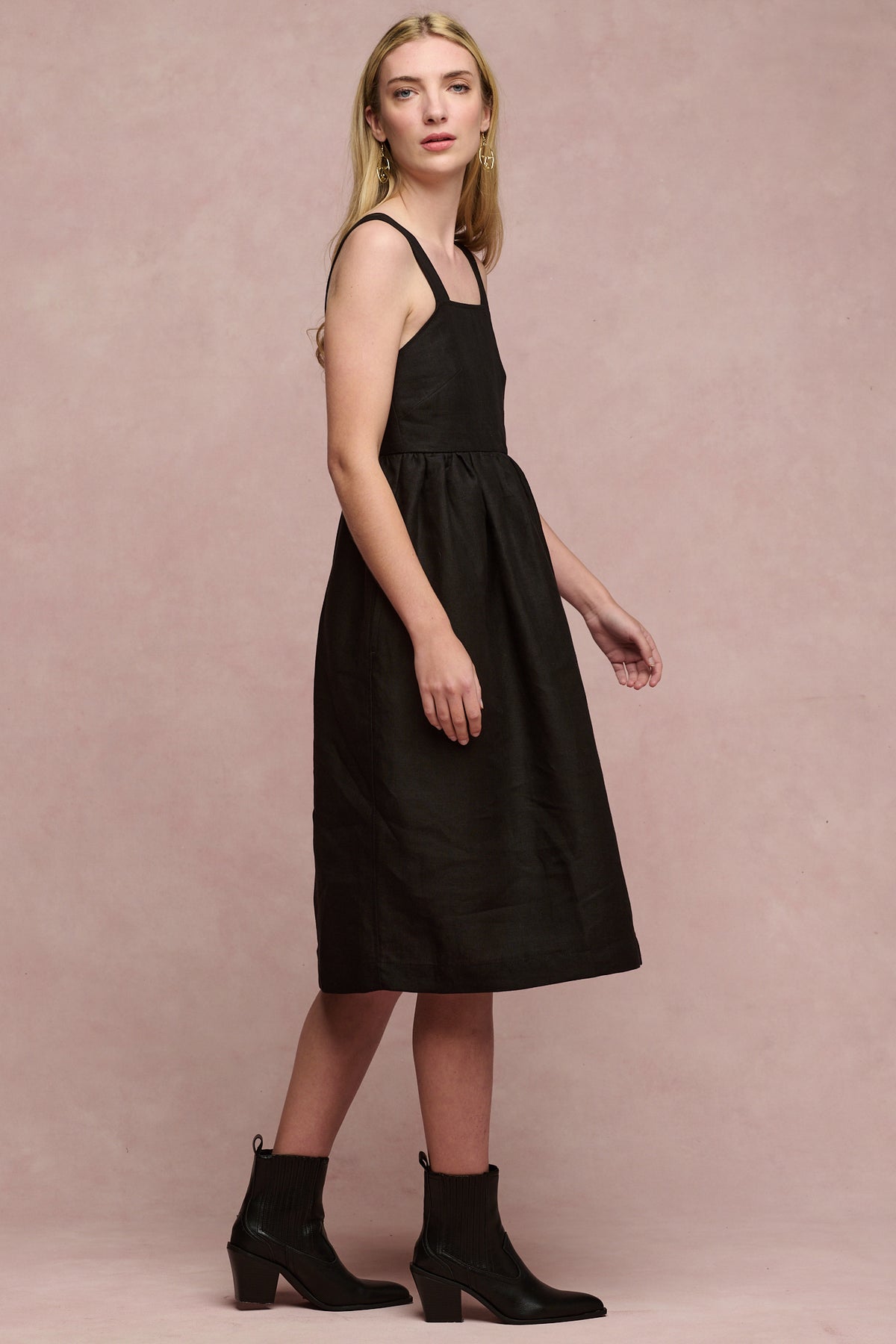 
            Full body image of female wearing linen sun dress in black paired with black heeled boots