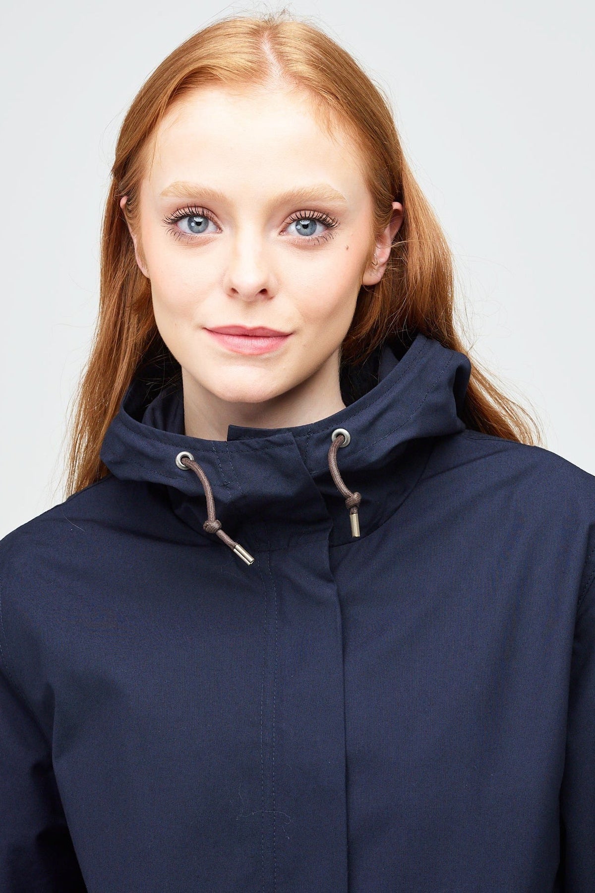 
            shoulders up image of a young, white model with ginger hear wearing a navy long parka