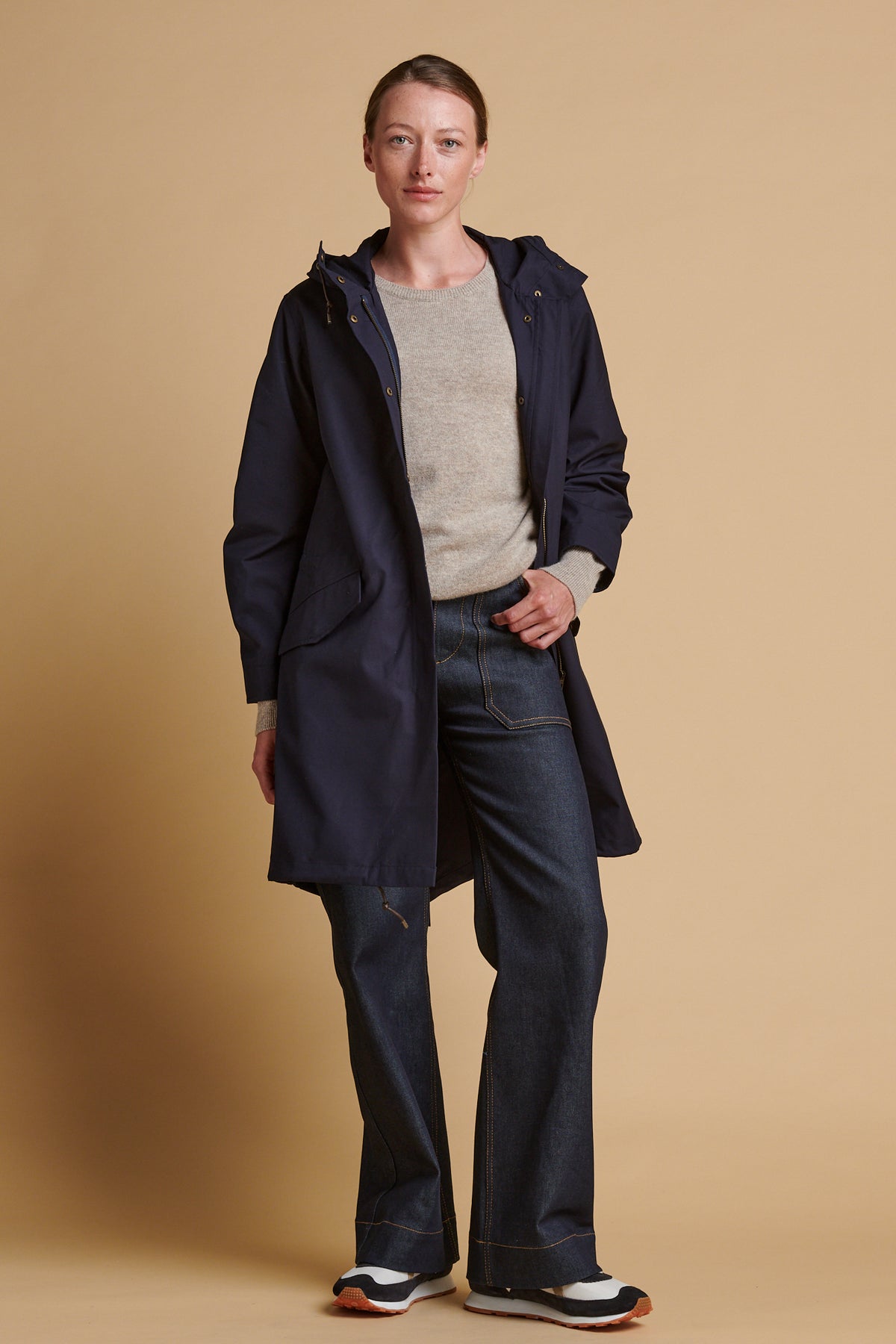 Female wearing long parka coat in navy.
