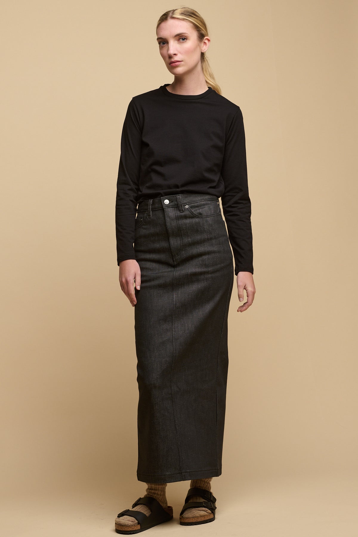 Full body image of female wearing long sleeve black t-shirt paired with Charlie denim maxi skirt in black