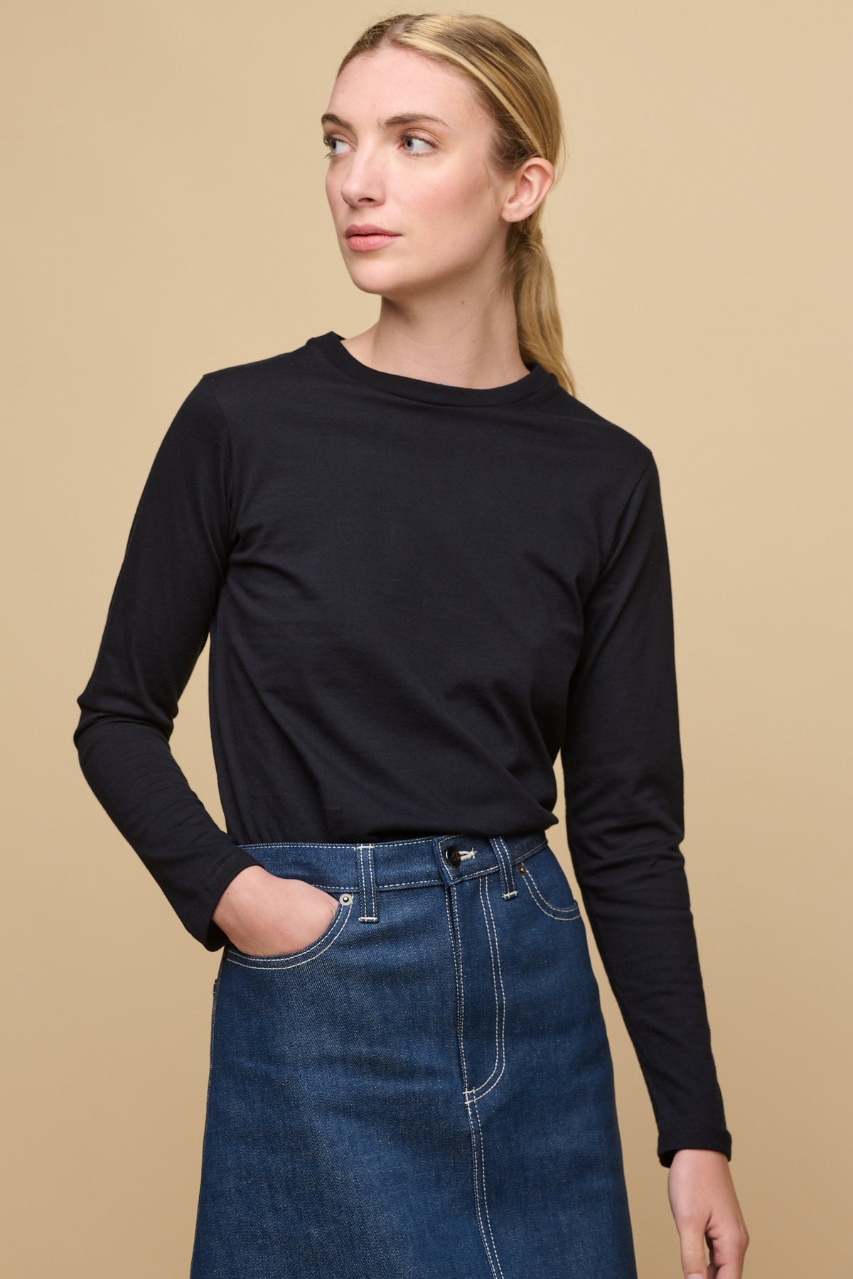 Female wearing long sleeve t-shirt in navy tucked into blue denim midi skirt