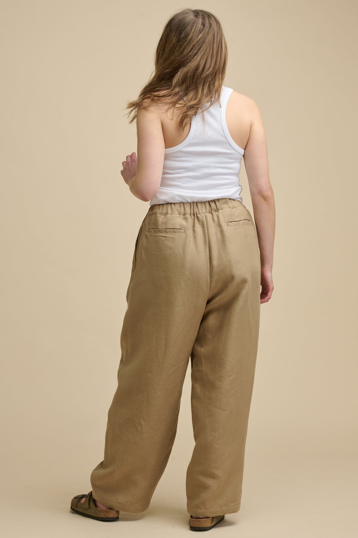 Full body image of the back of Lorna elasticated waist linen trousers in truffle with two back jet pockets