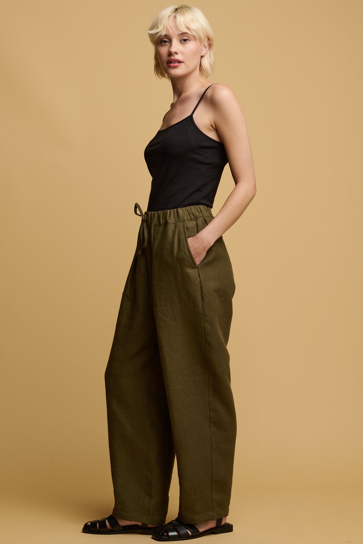 Female with blond hair wearing Community Clothing Lorna elasticated waist linen trouser in olive paired with a black camisole tucked in