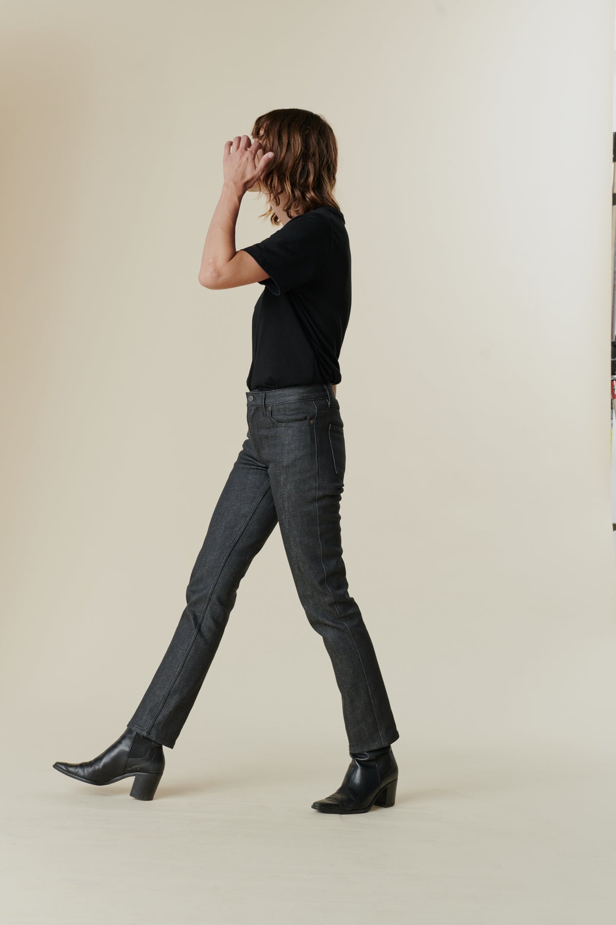 Full body image of side of female wearing mid rise straight leg jeans in black