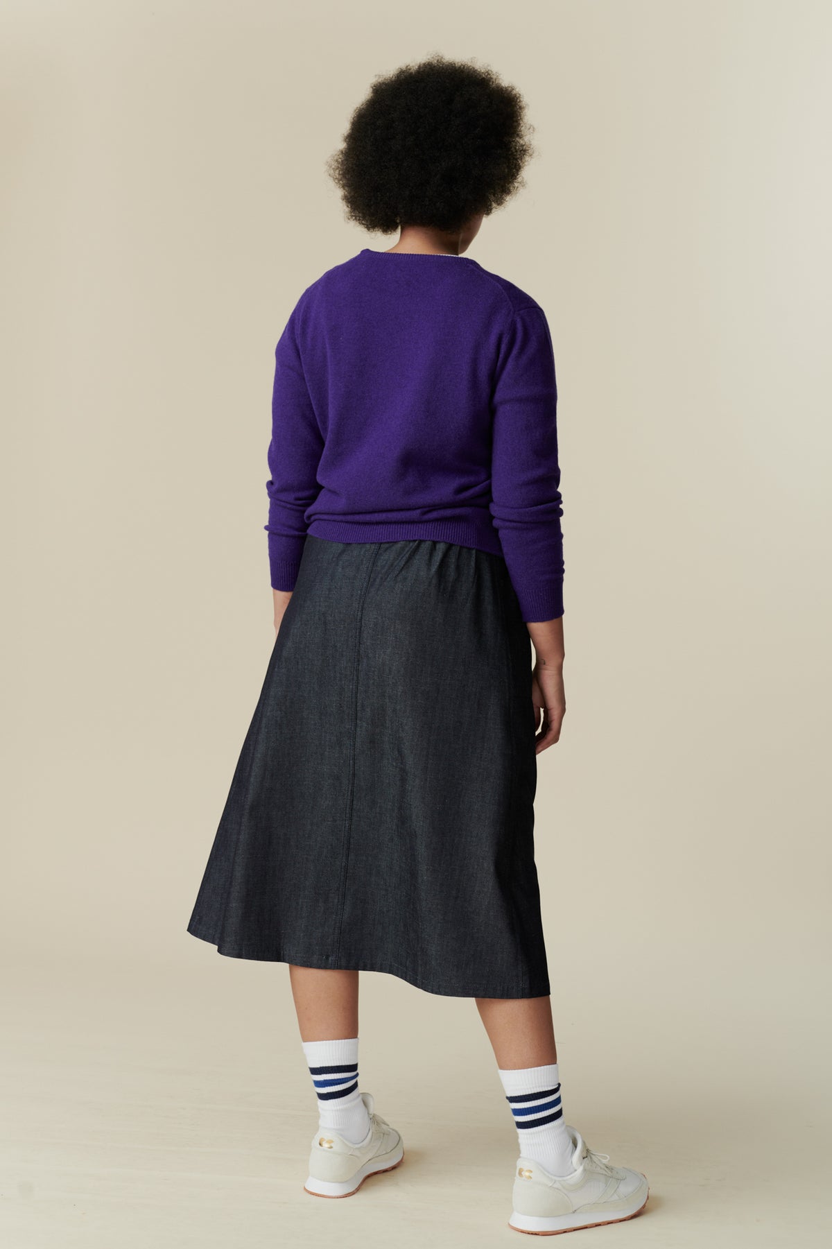 The back of female wearing midi skirt in denim paired with lambswool jumper in purple