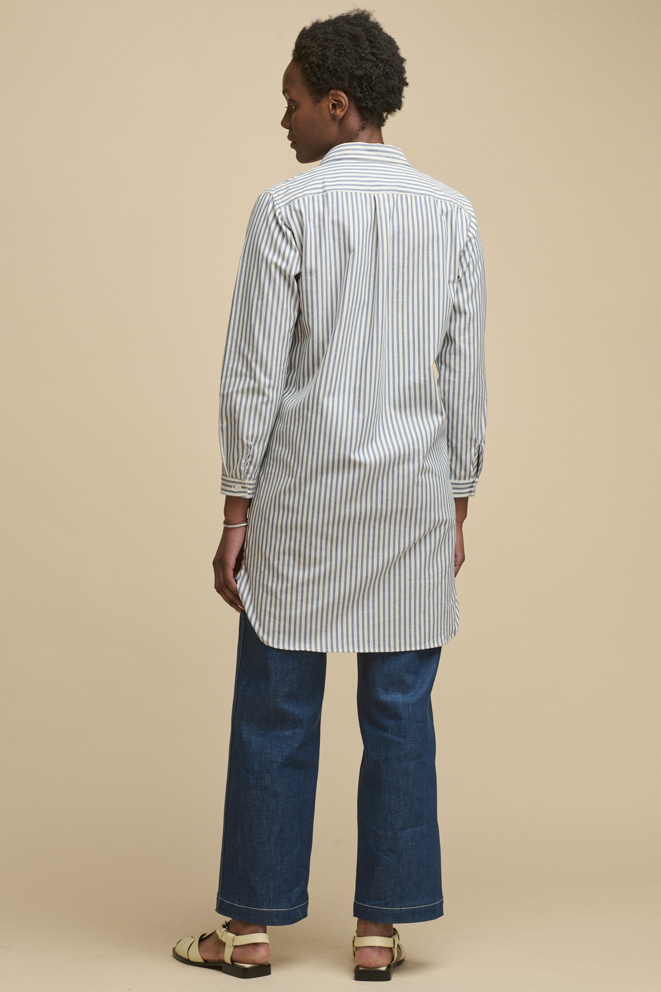 Full body image of black female wearing women's Olivia shirt dress in navy white stripe. Worn over blue work jeans 