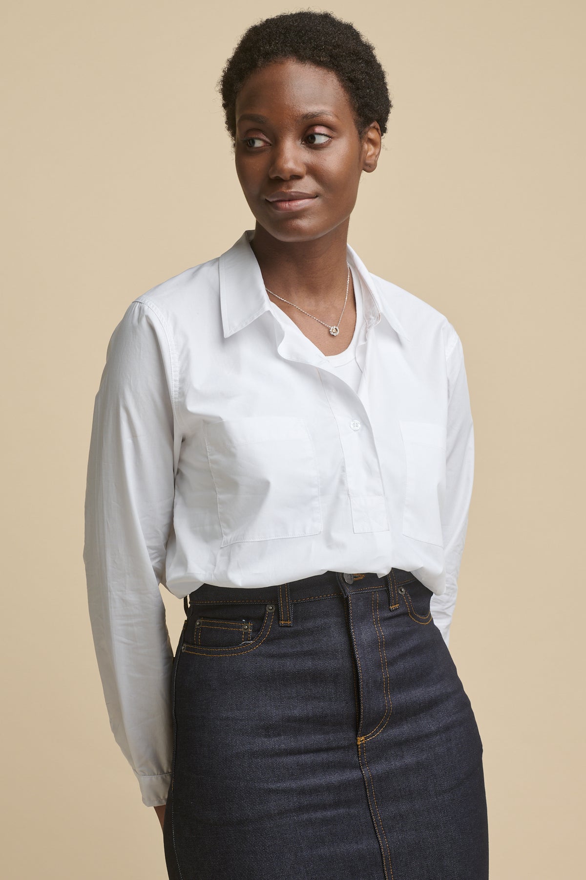 
            Thigh up image of the front of black female wearing Olivia half placket lightweight cotton shirt in white, worn over racer back vest in white paired with Maxi skirt in indigo