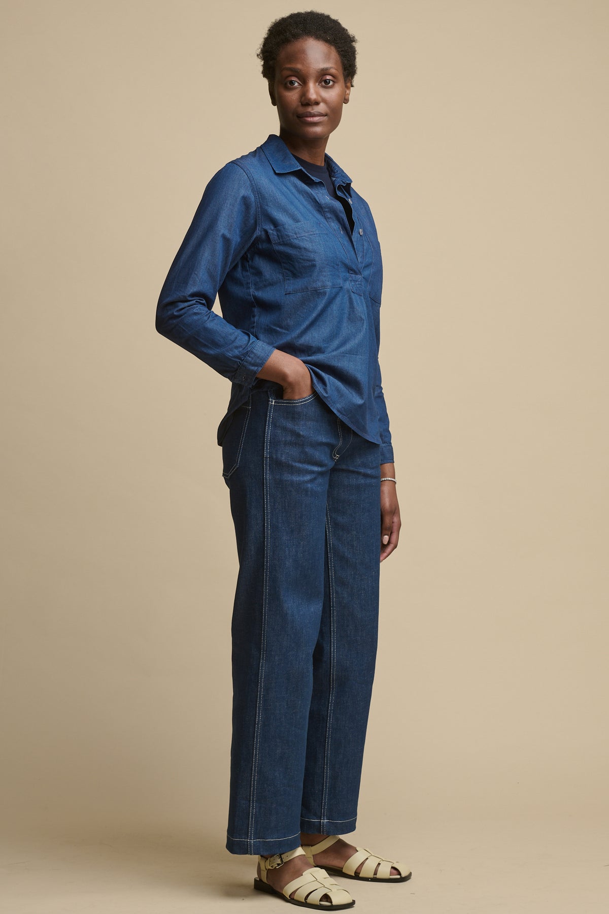 Full body image of female wearing Olivia half placket lightweight shirt in indigo paired with women's work jeans in blue