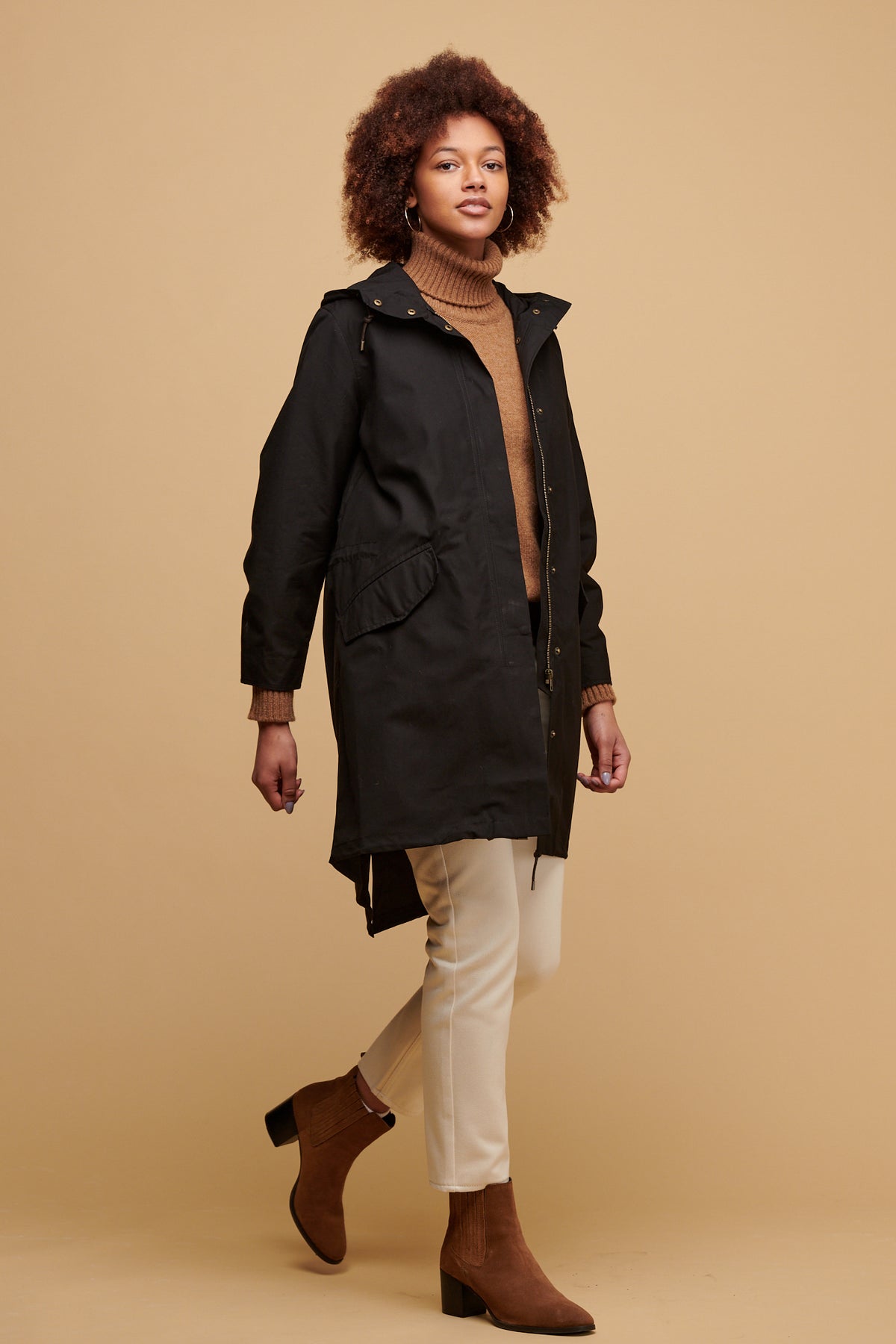 Female wearing women's parka coat in black worn over lambswool roll neck jumper in dark camel paired with gloria jean in ecru
