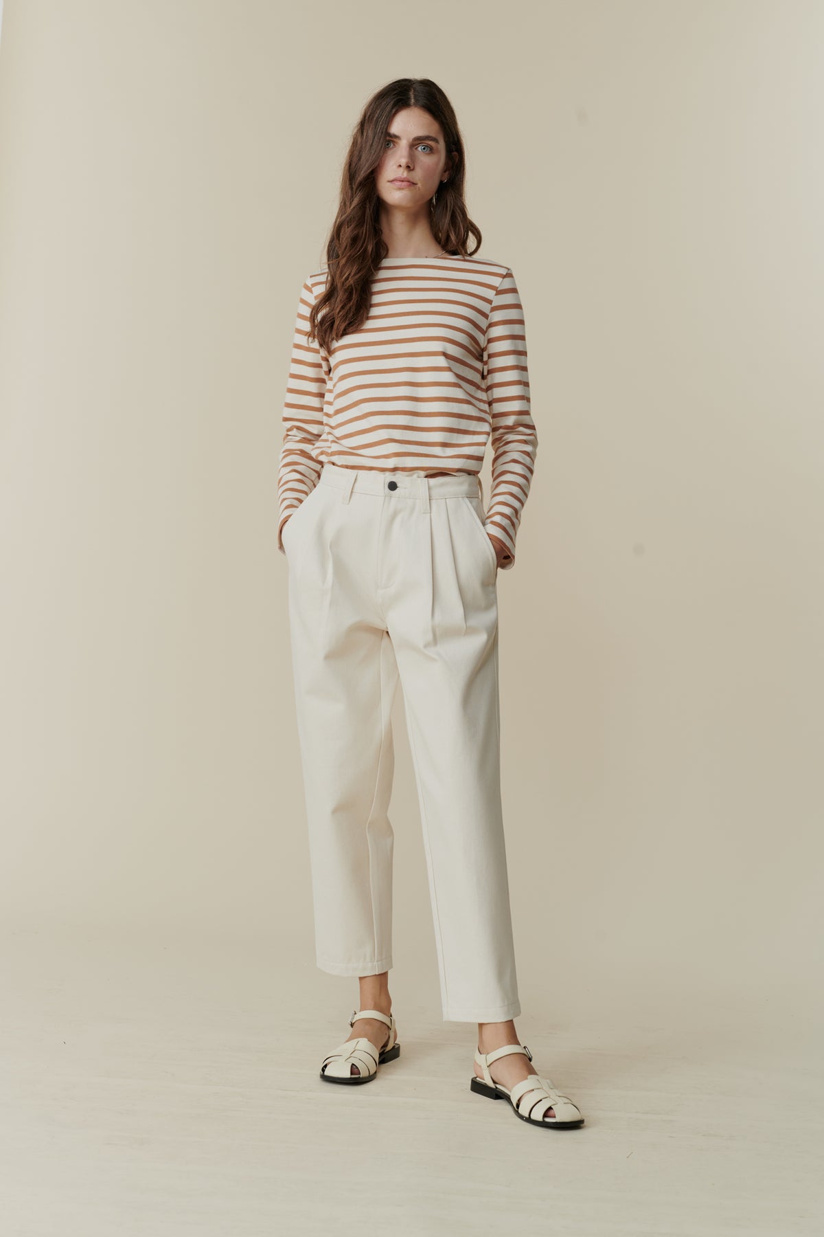 
            Full body front image of white female with long brunette hair wearing women&#39;s pleated jeans in ecru, paired with breton in ecru cinnamon