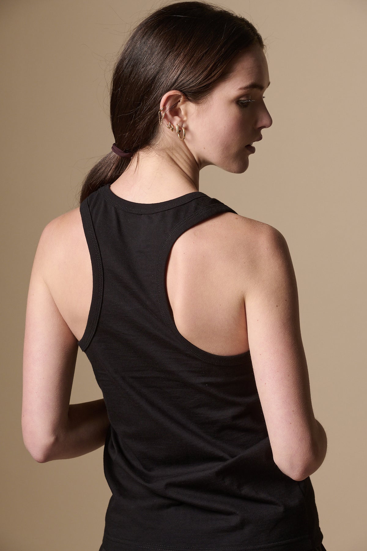 
            Image shows the back of white female with brunette hair in ponytail, wearing racer back vest plastic free in black.