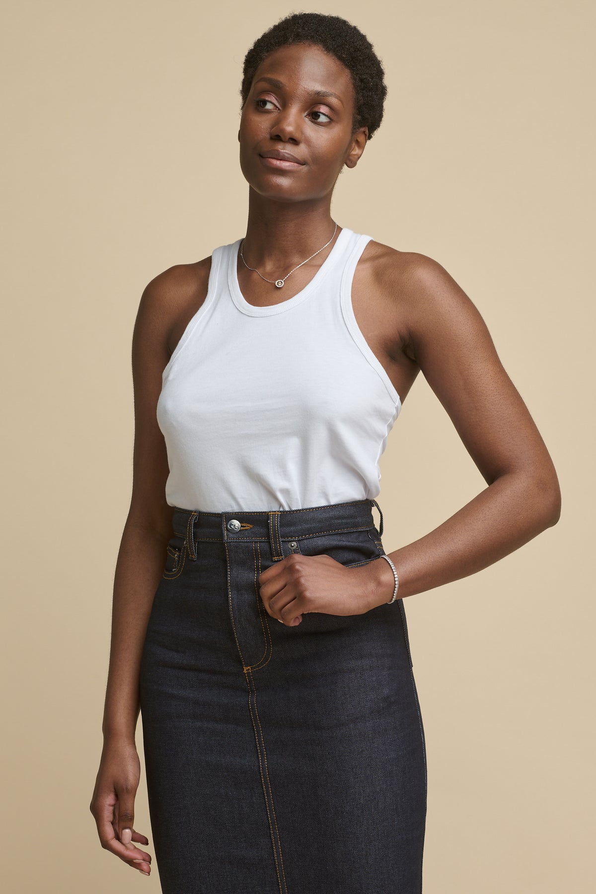 Thigh up image of the front of black female wearing racer back vest in white