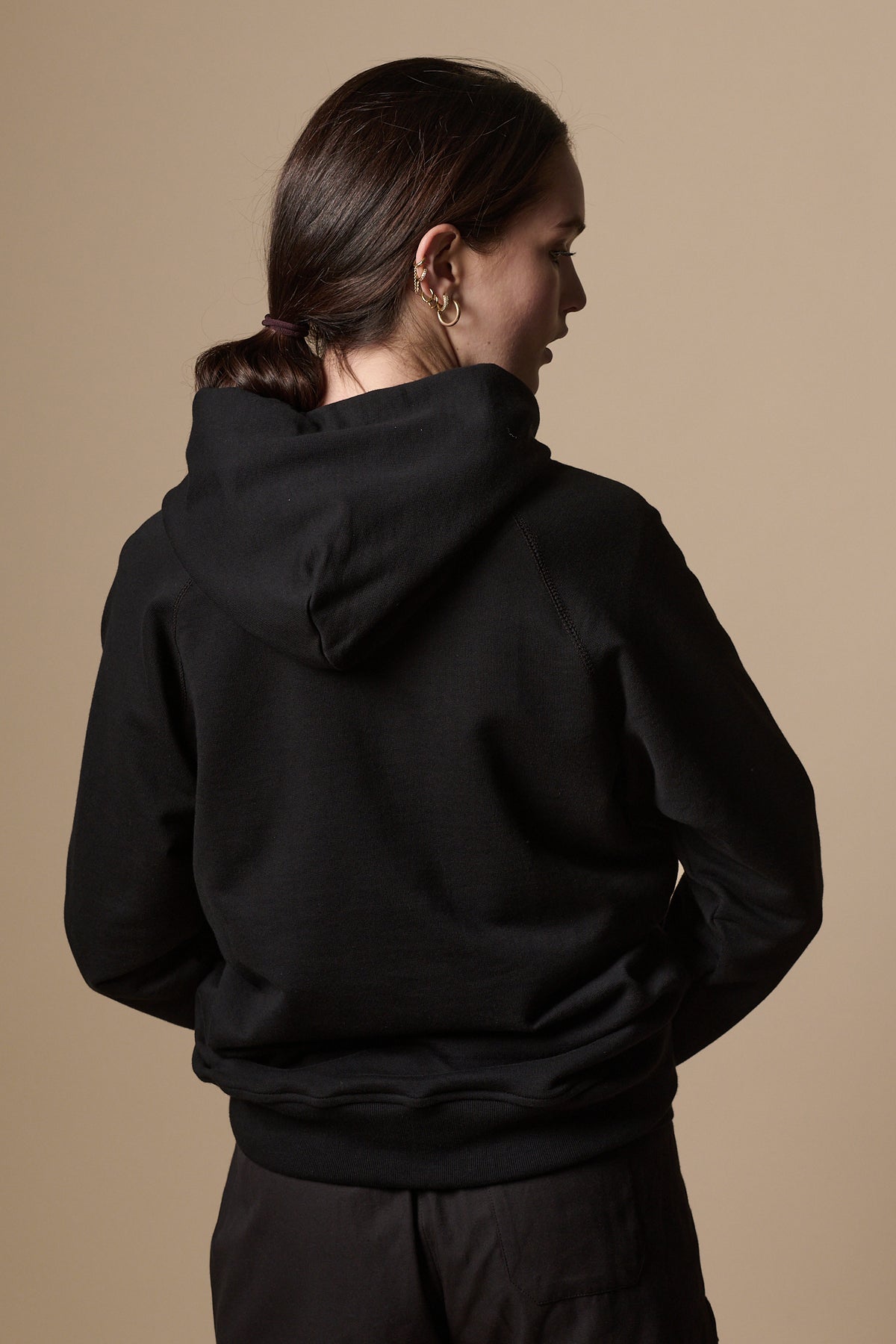 Back of female wearing women's raglan hooded sweatshirt plastic free in black