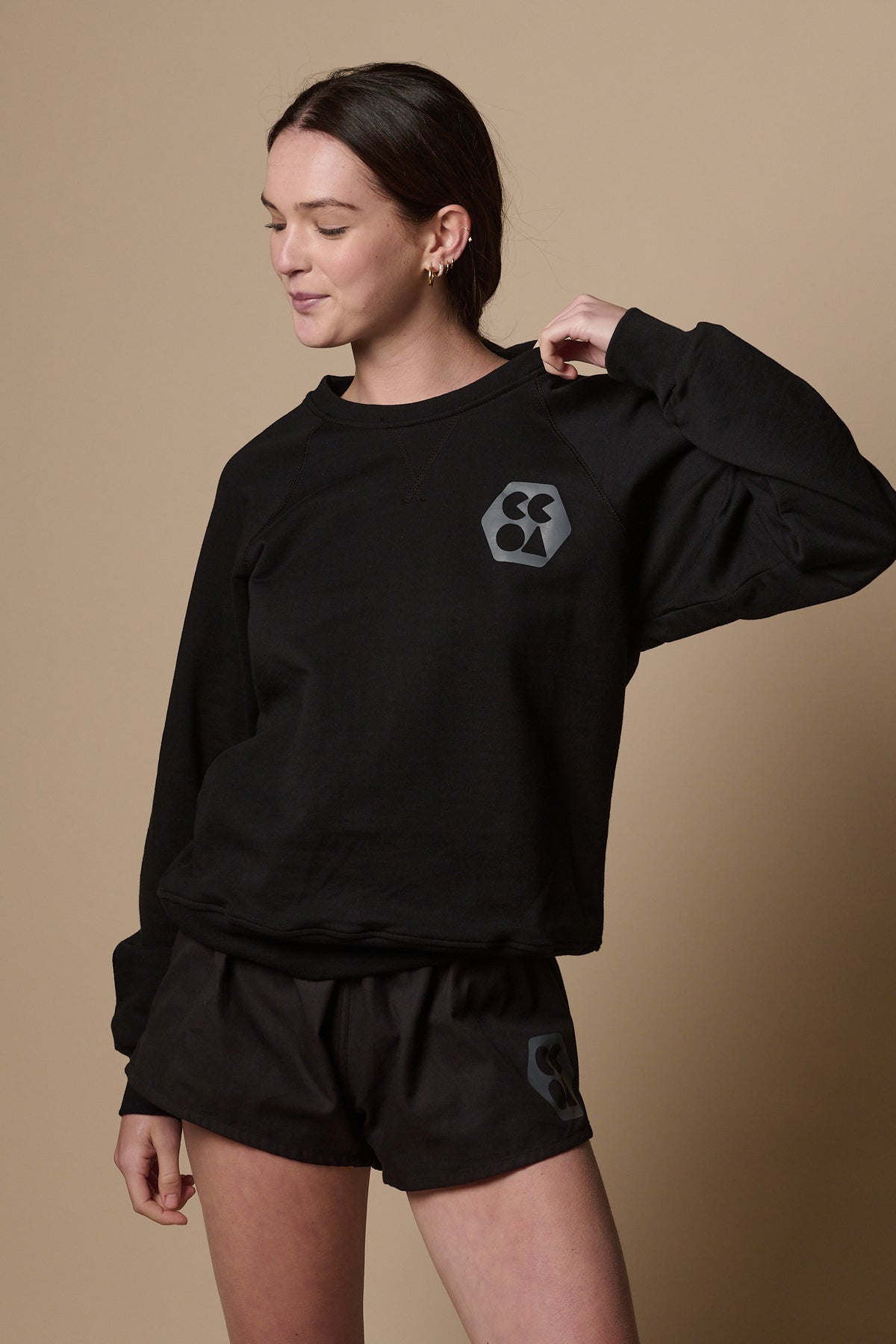 
            Female wearing raglan sweatshirt in black with CCOA logo