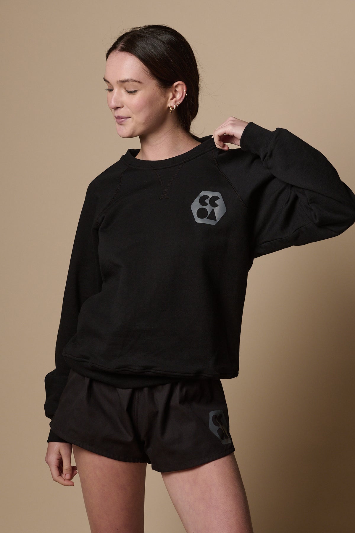 Female wearing raglan sweatshirt in black with CCOA logo