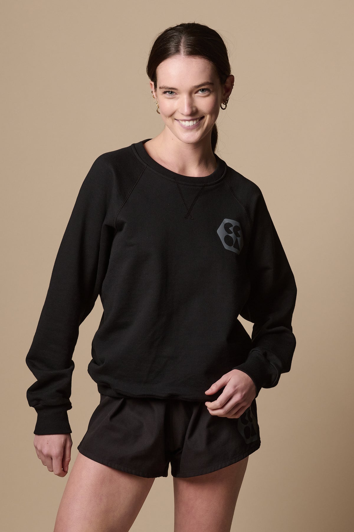 
            Smiley female wearing raglan sweatshirt in black with CCOA logo