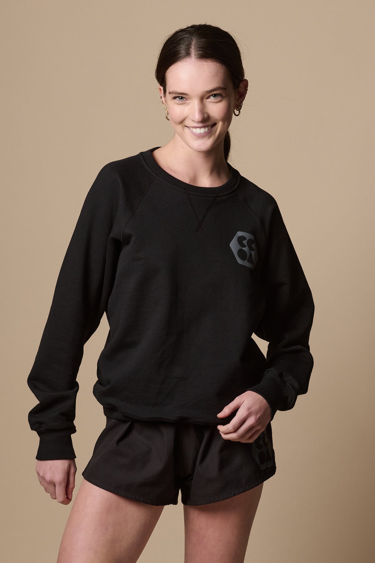 Smiley female wearing raglan sweatshirt in black with CCOA logo