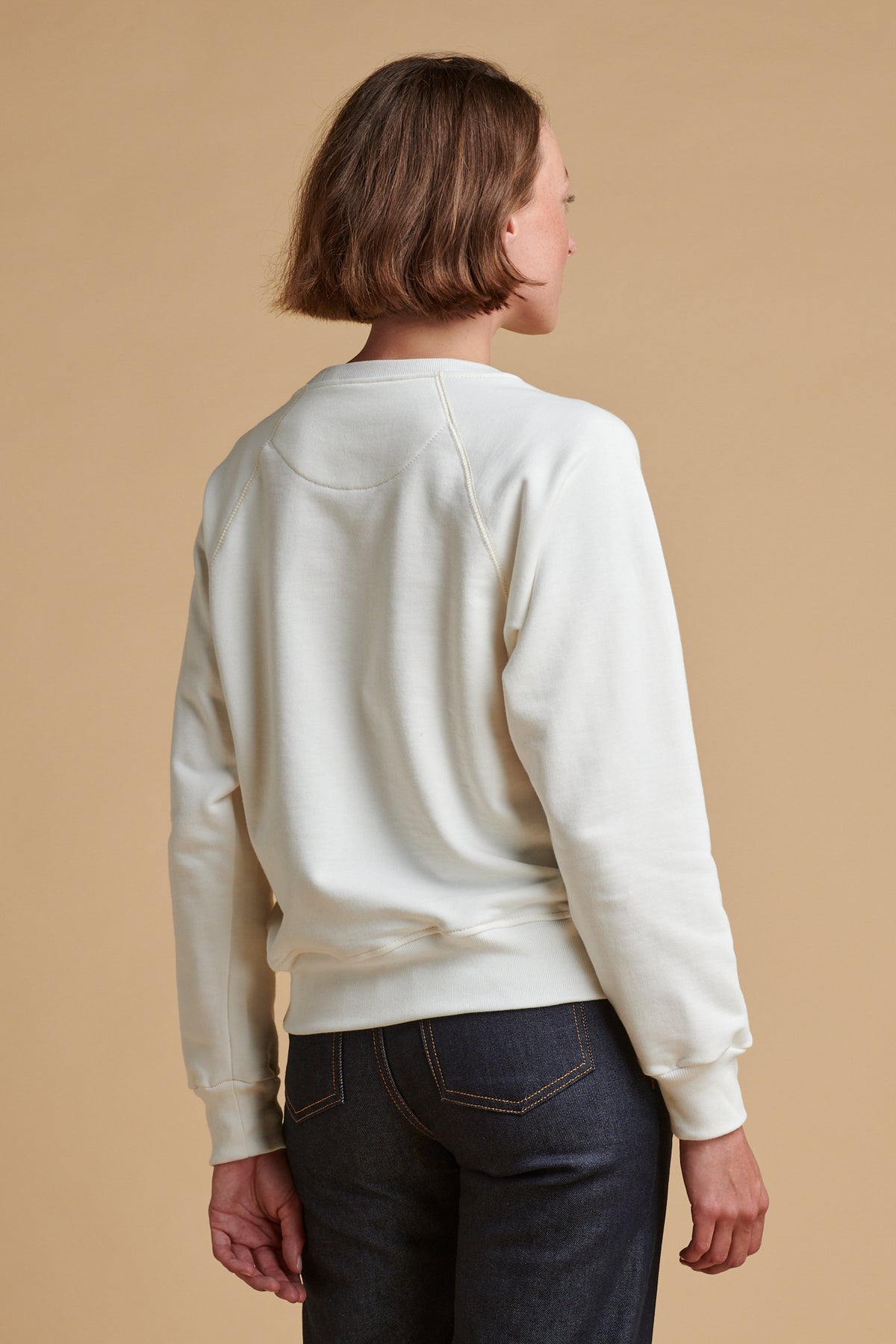 the back of female wearing raglan sweatshirt plastic free in bone.