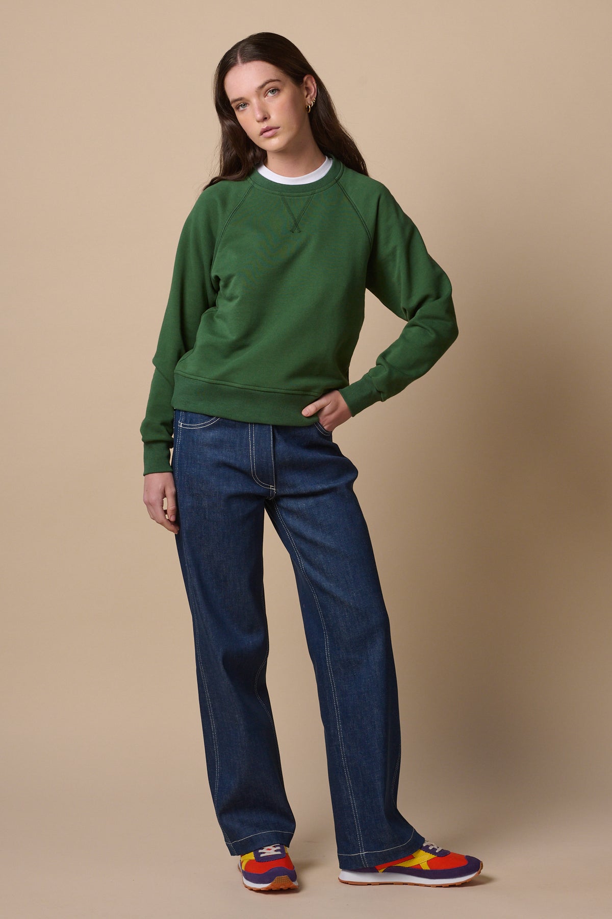 Female wearing raglan sweatshirt in bottle green with women's work jeans in blue