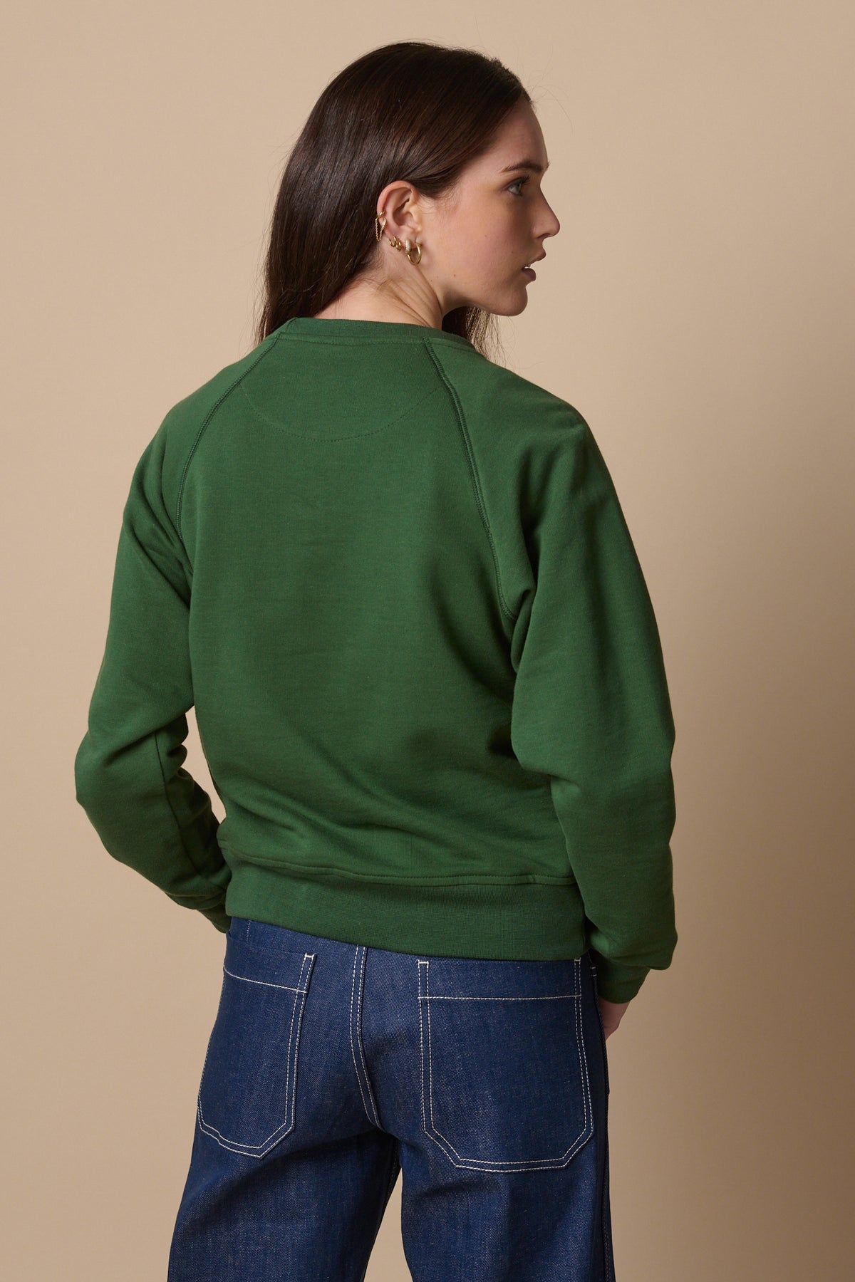 Thigh up image of the back of raglan sweatshirt in bottle green
