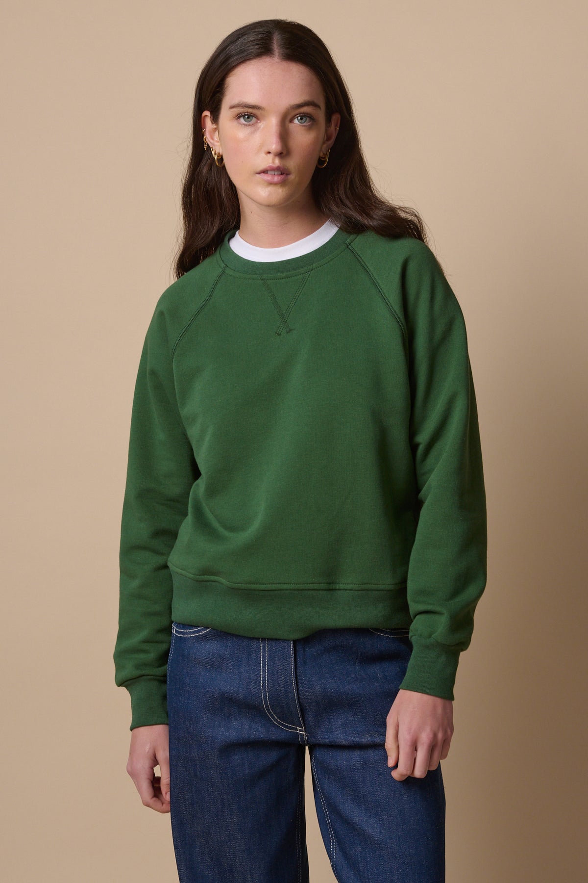 Thigh up image of female wearing raglan sweatshirt in bottle green