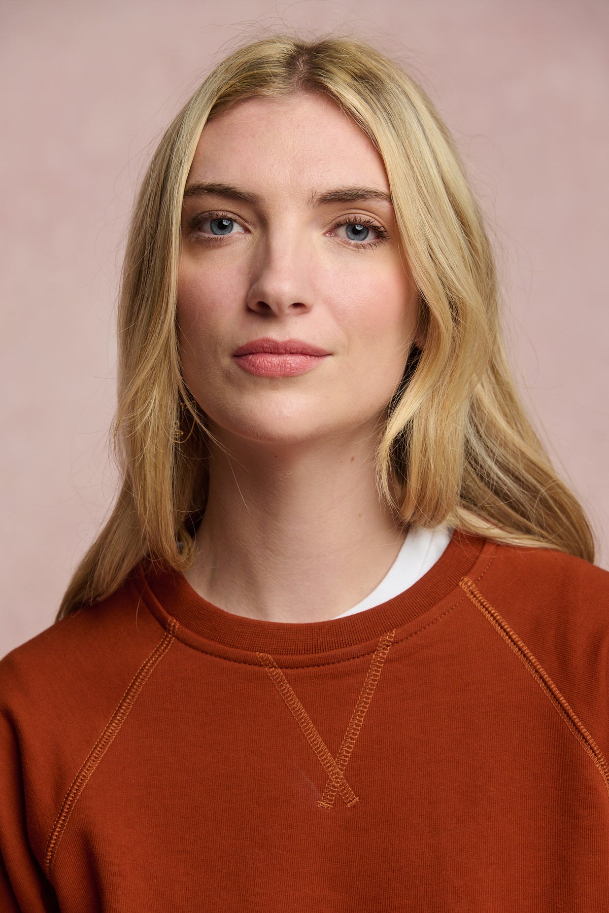 Portrait of female wearing raglan sweatshirt in cinnamon layered over crew neck t shirt in white