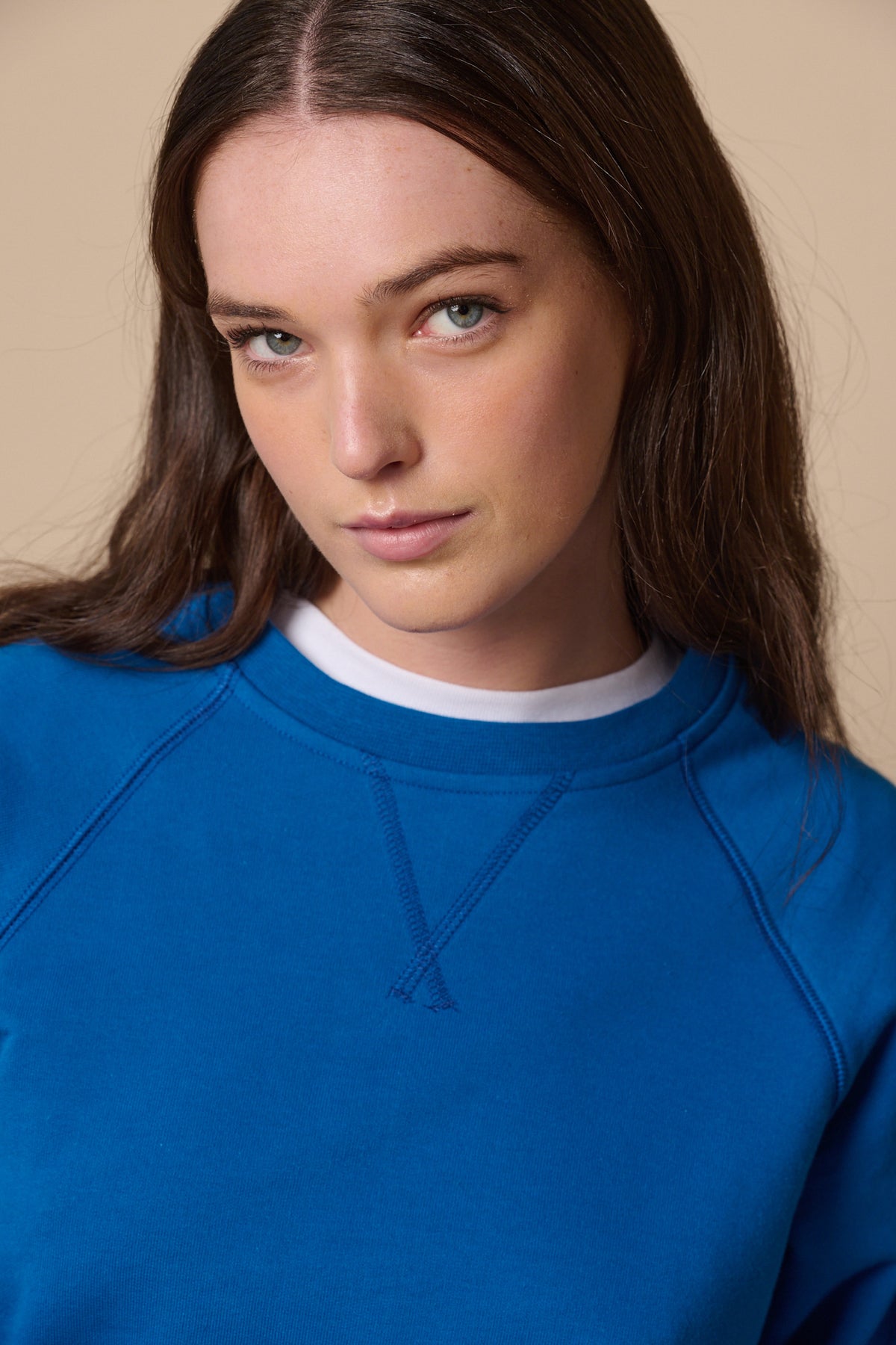
            Portrait of brunette female wearing raglan sweatshirt in cobalt 