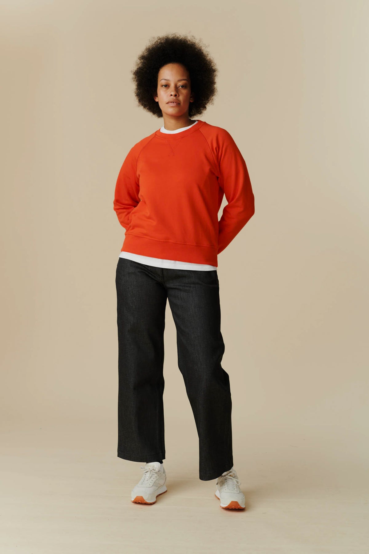 Full body image of female wearing raglan sweatshirt in flame red