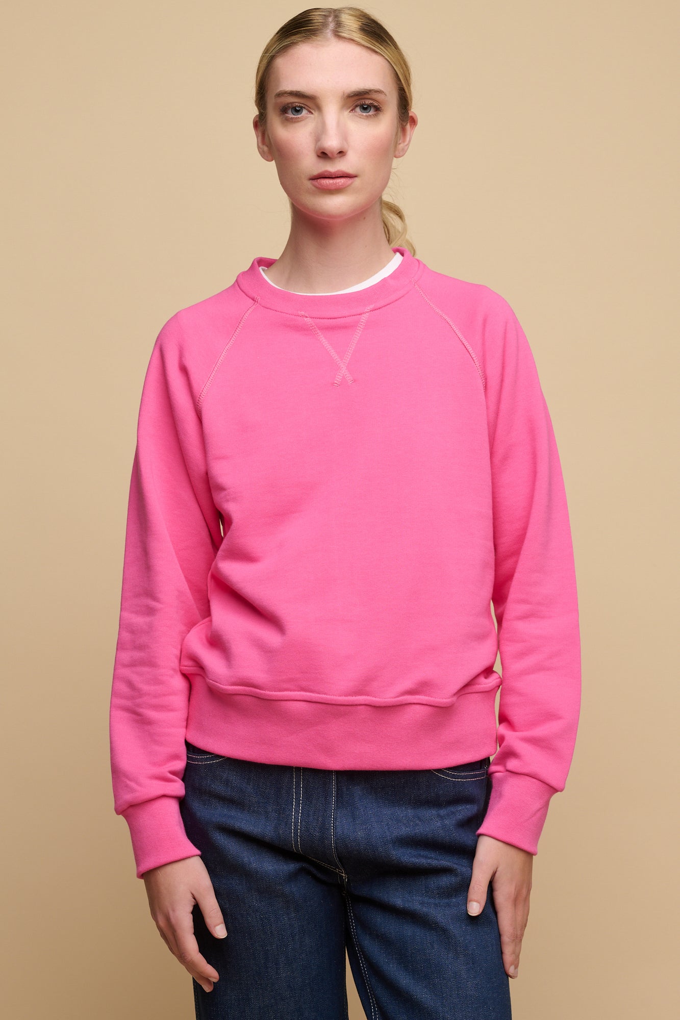 Thigh up of female wearing raglan sweatshirt in fuchsia pink worn over crew neck t shirt in white