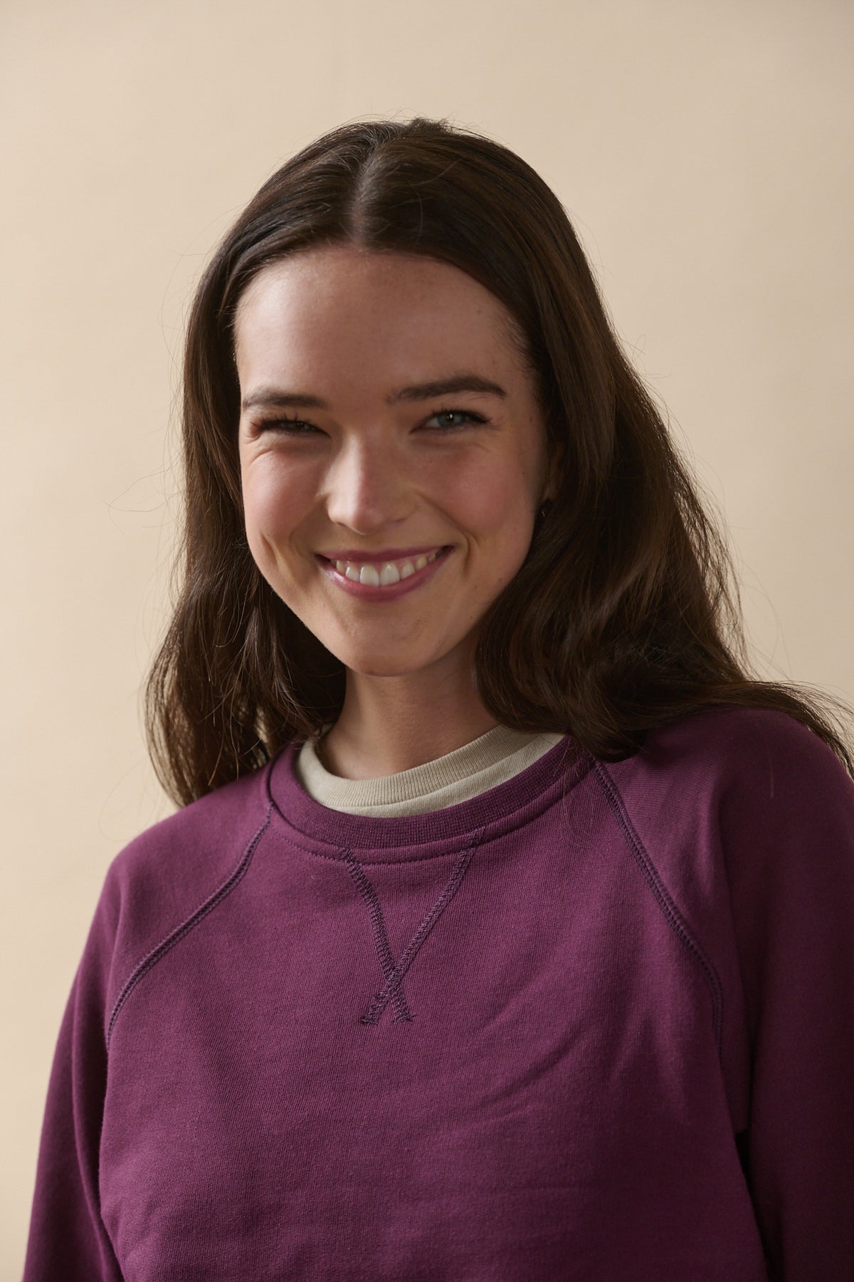 Smiley portrait of brunette female wearing raglan sweatshirt in plum
