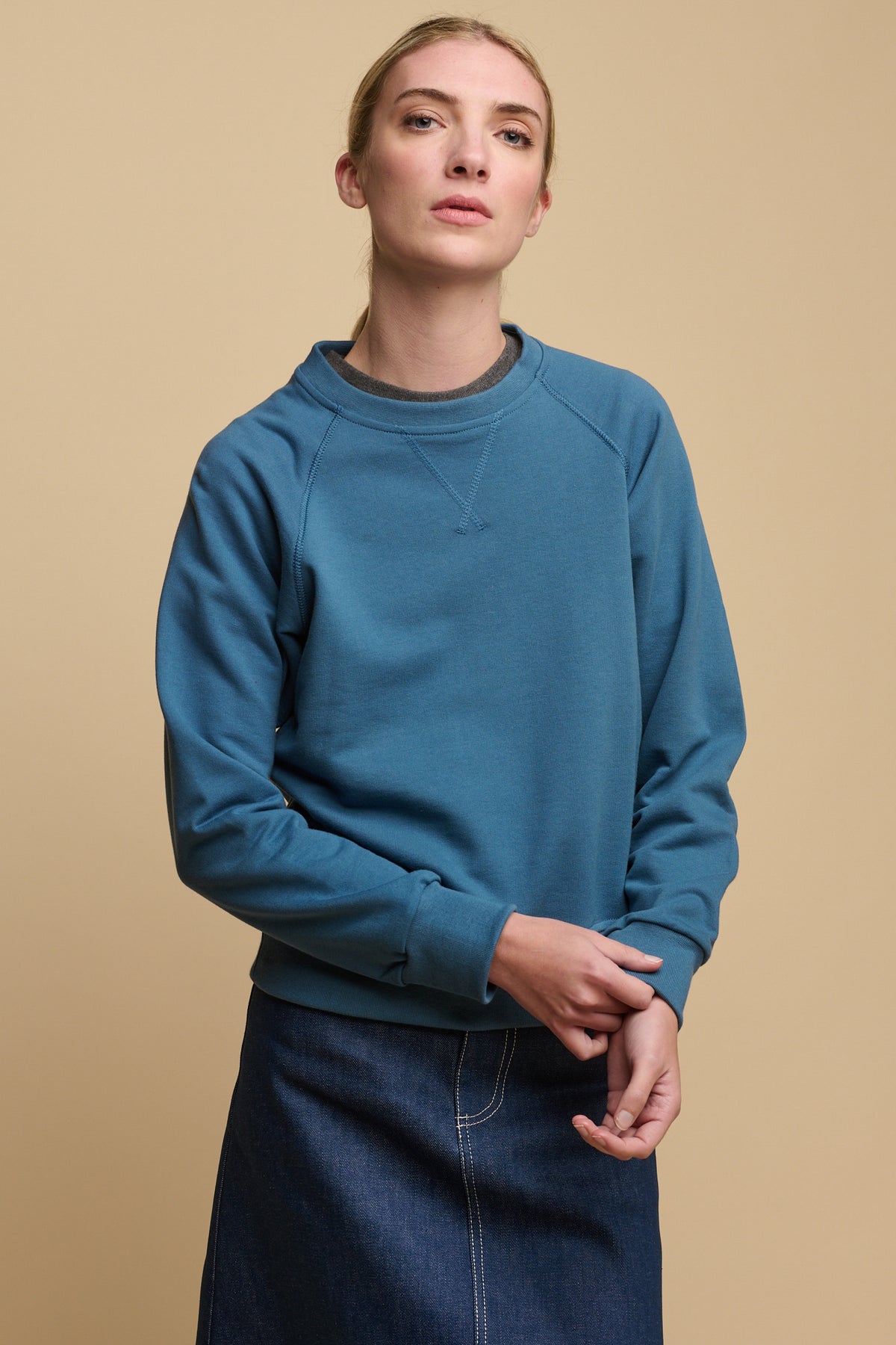 Female wearing raglan sweatshirt in RAF blue worn over crew neck t shirt in charcoal paired with Bobbie denim midi skirt in blue
