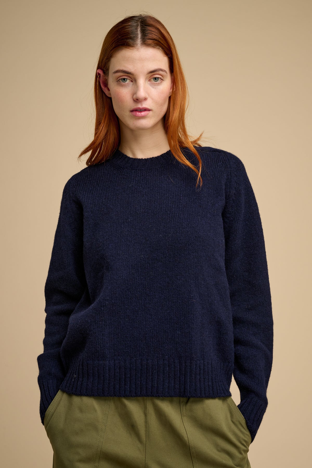 Woman wearing a navy sweater against a beige background