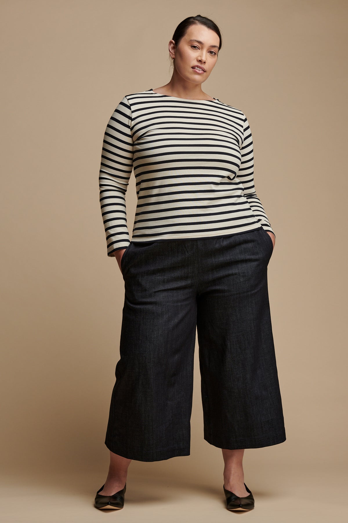 Female with brown hair tied back wearing long sleeve Breton top paired with short pj trousers in indigo denim wityh her hands in the side pockets.