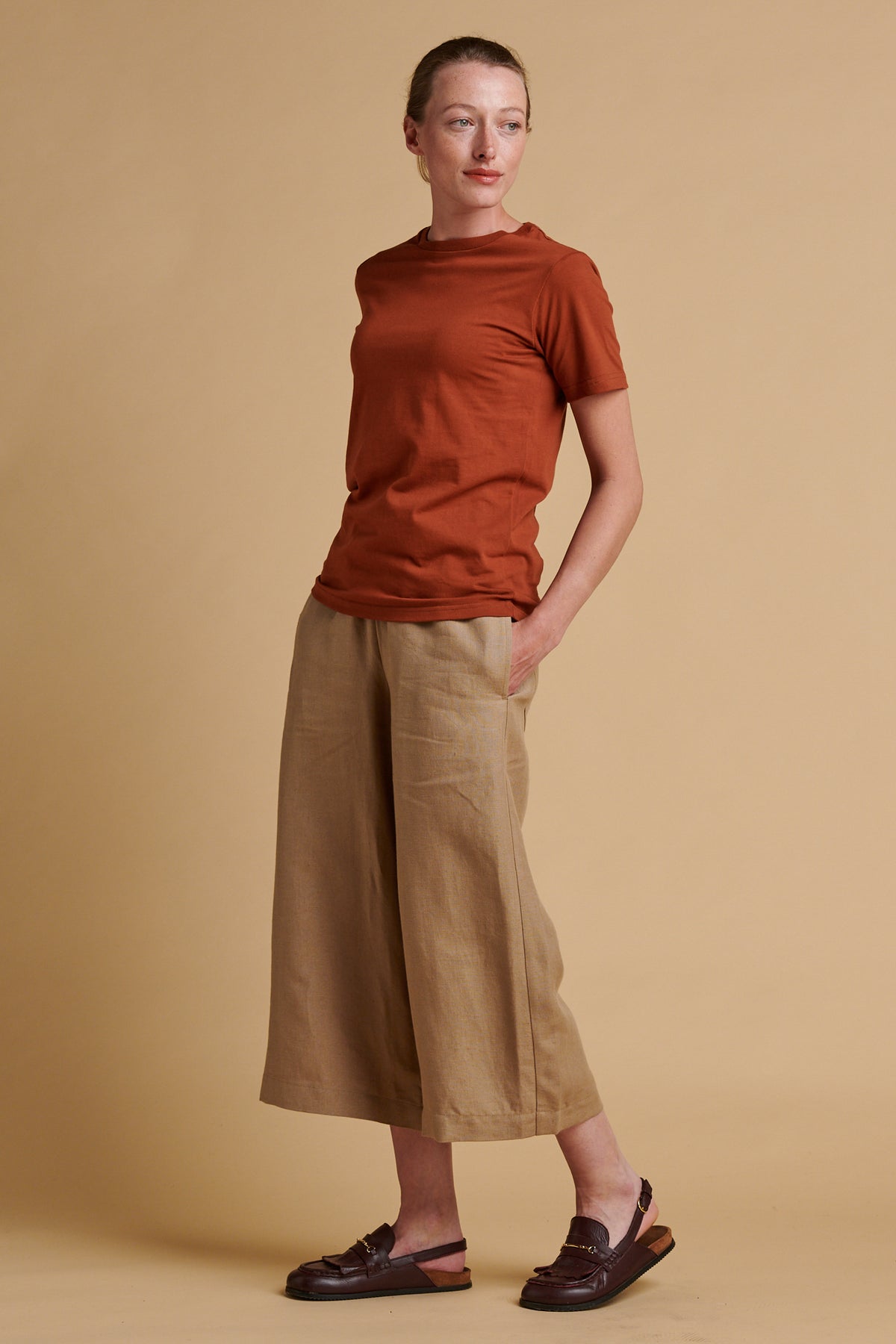 Female wearing short pj trousers in truffle linen paired with short sleeve crew neck t shirt in cinnamon.