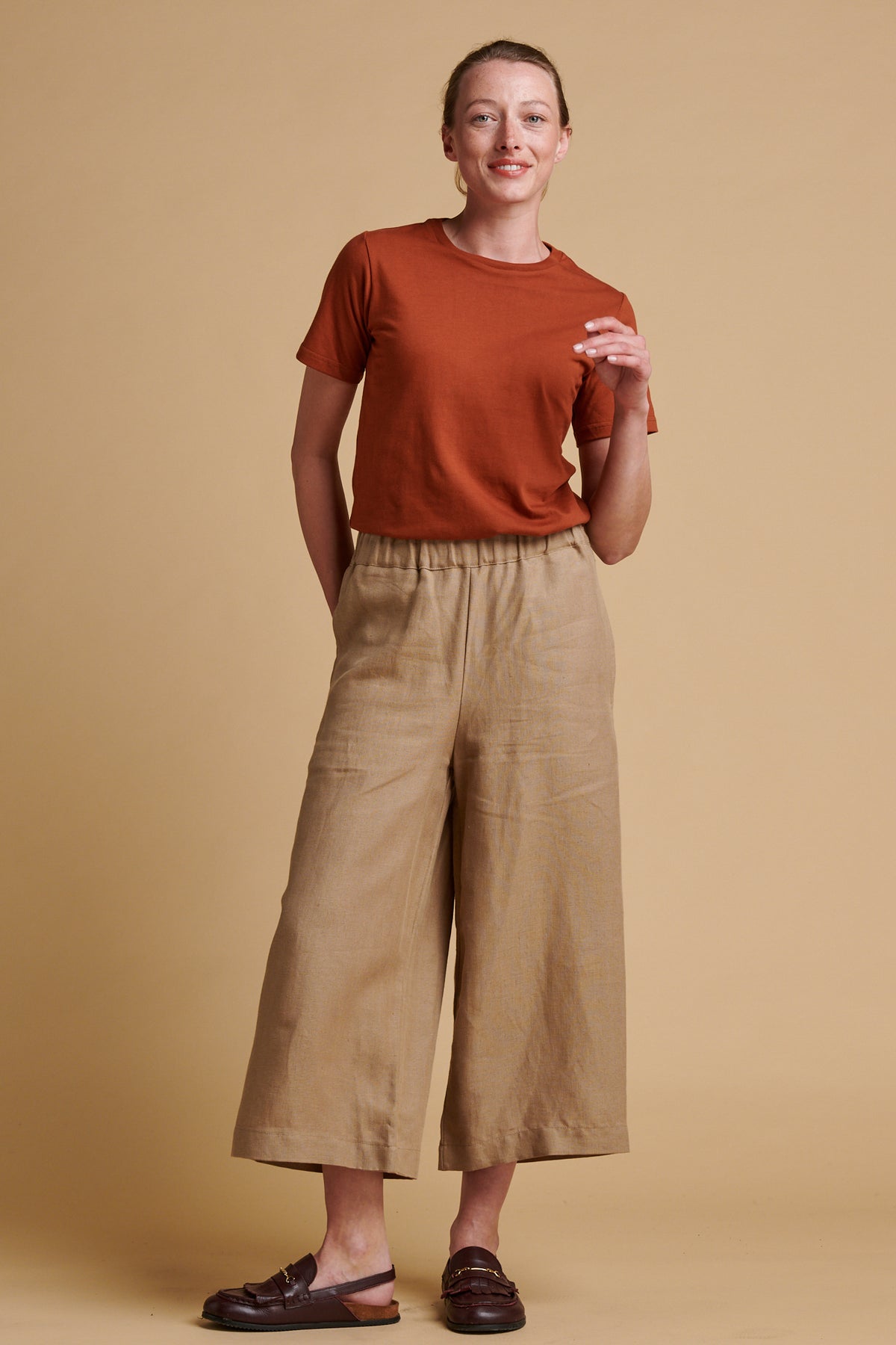 Female wearing short pj trousers in truffle linen paired with short sleeve crew neck t shirt in cinnamon.