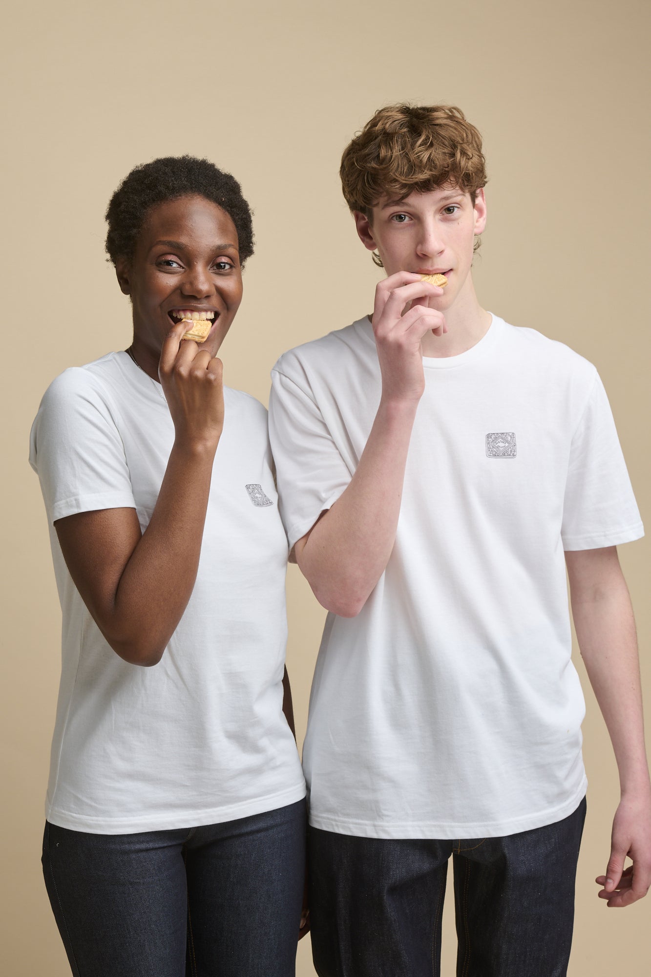 Thigh up image of female and male young models wearing short sleeve white t shirts with graphic print of custard cream line drawing on the chest