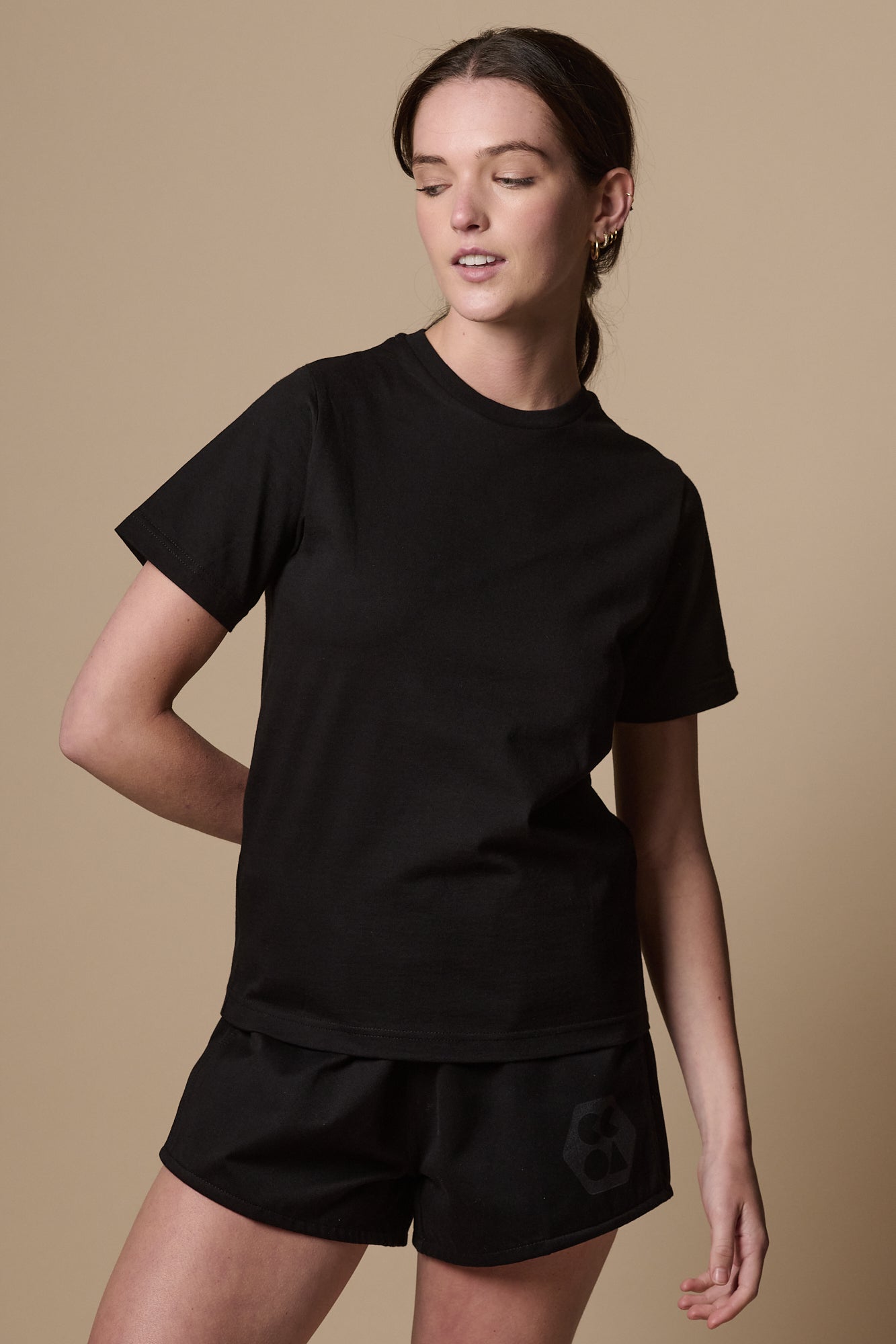 White female with hair tied back wearing short sleeve, crew neck t shirt plastic free in black.