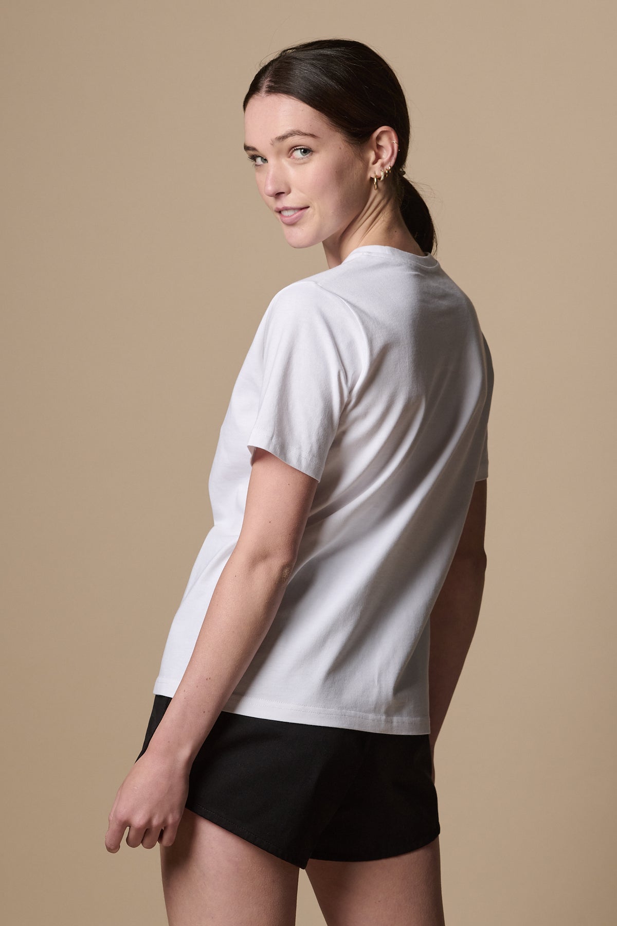 Image showing the back of female looking back to the camera wearing short sleeve t shirt in white.