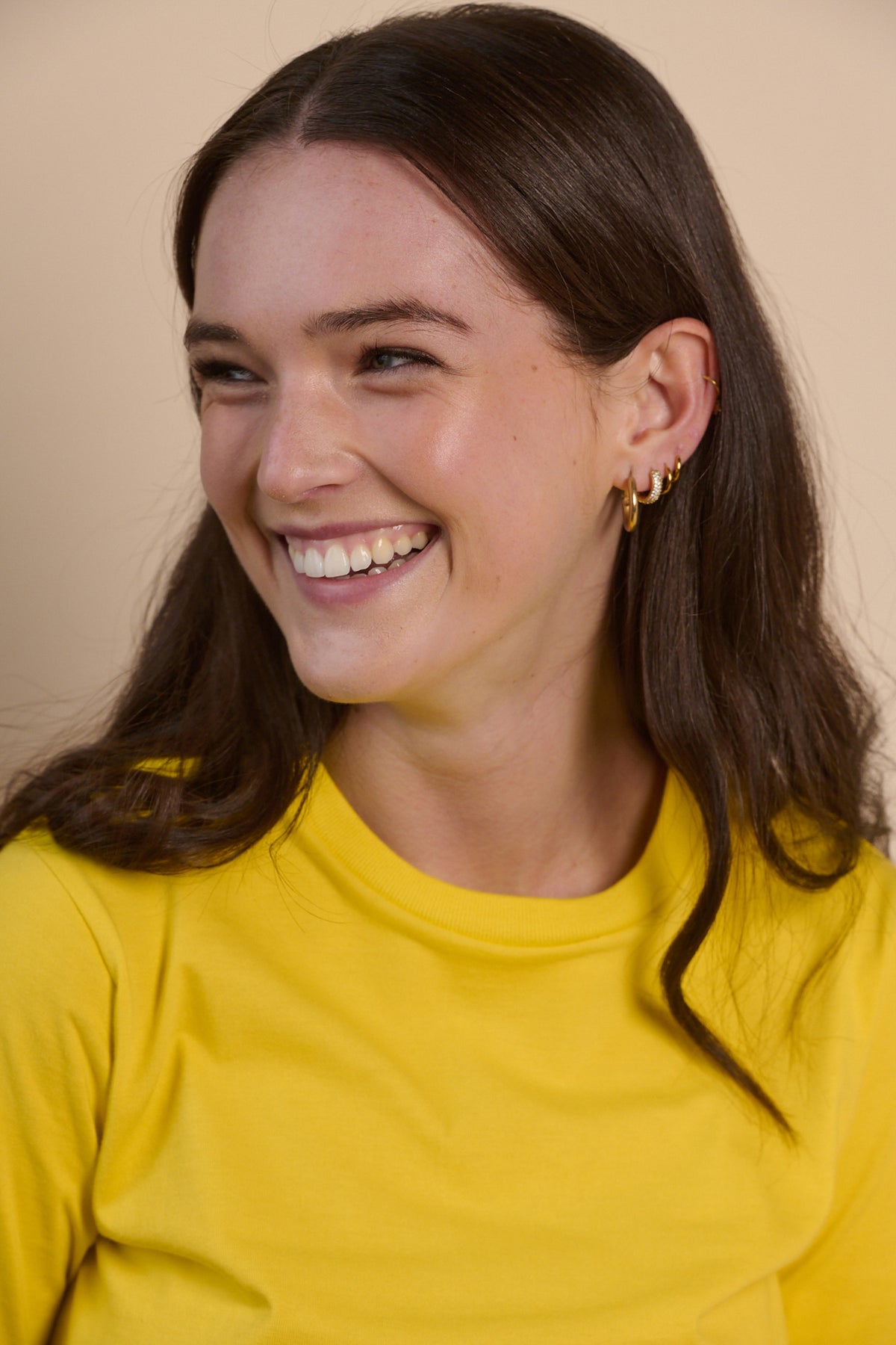 Portrait of smiley female with long brunette hair wearing short sleeve crew neck t shirt in canary yellow